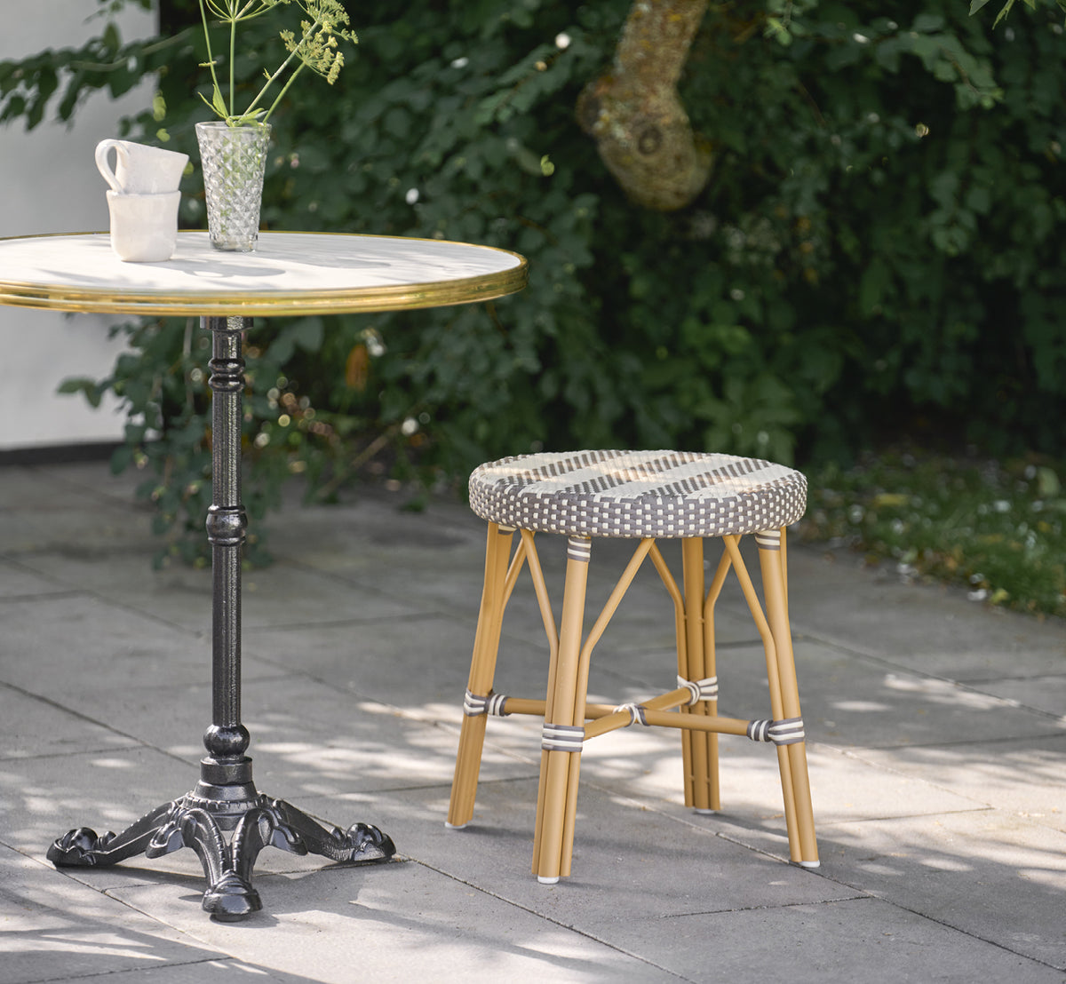 Esta es una imagen de estilo de vida de Simone taburete exterior en almond aluminium frame striped cappuccino ivory artfibre. Estilizado en un interior luminoso.