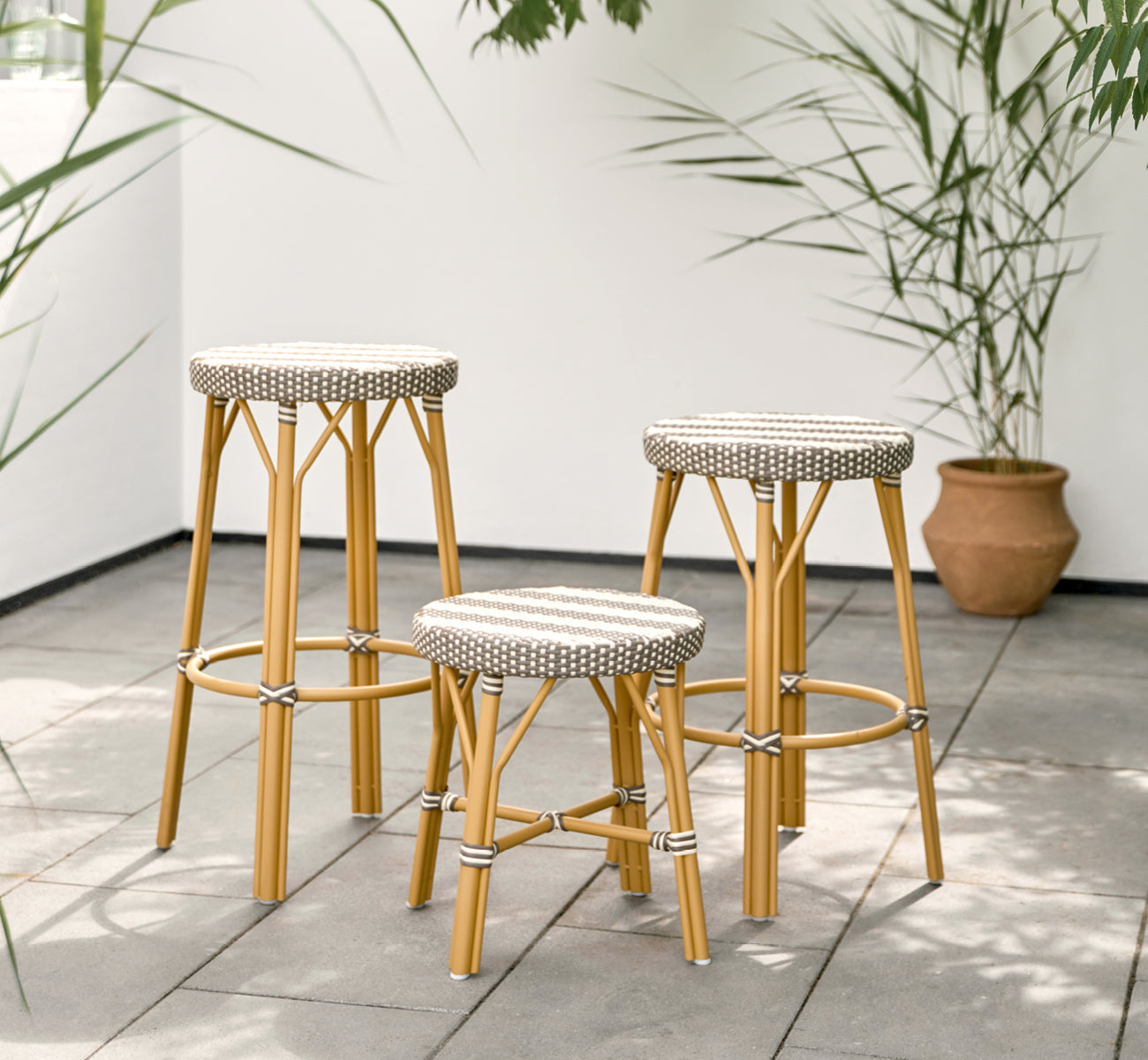 Esta es una imagen de estilo de vida de Simone taburete exterior en almond aluminium frame striped cappuccino ivory artfibre. Estilizado en un interior luminoso.