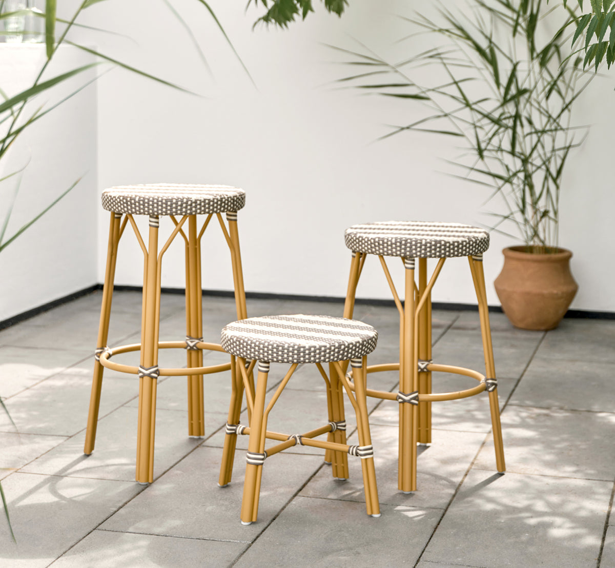 Esta es una imagen de estilo de vida de Simone taburete exterior en almond aluminium frame striped cappuccino ivory artfibre. Estilizado en un interior luminoso.