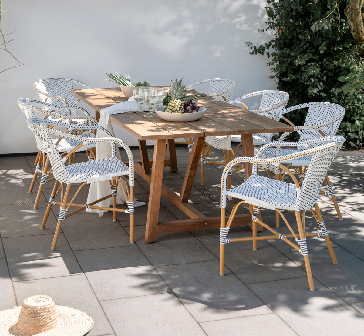 Esta es una imagen de estilo de vida de Madeleine silla de comedor exterior en almond aluminium frame white w cappuccino dot ArtFibre. Comedor de jardín con mesa de teca.