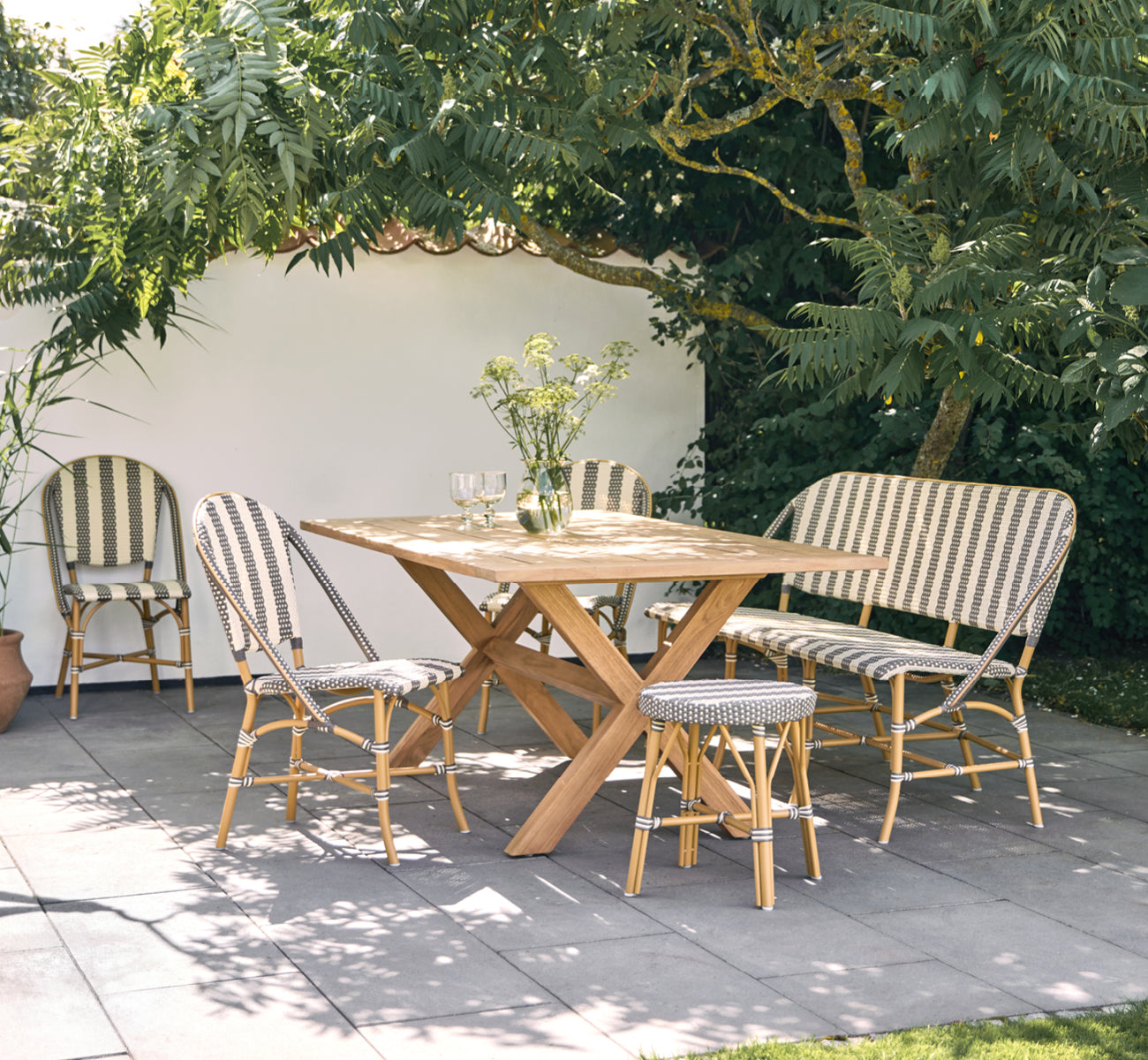 Esta es una imagen de estilo de vida de Sofie banco exterior de 3 plazas en almond aluminium frame striped cappuccino ivory artfibre.