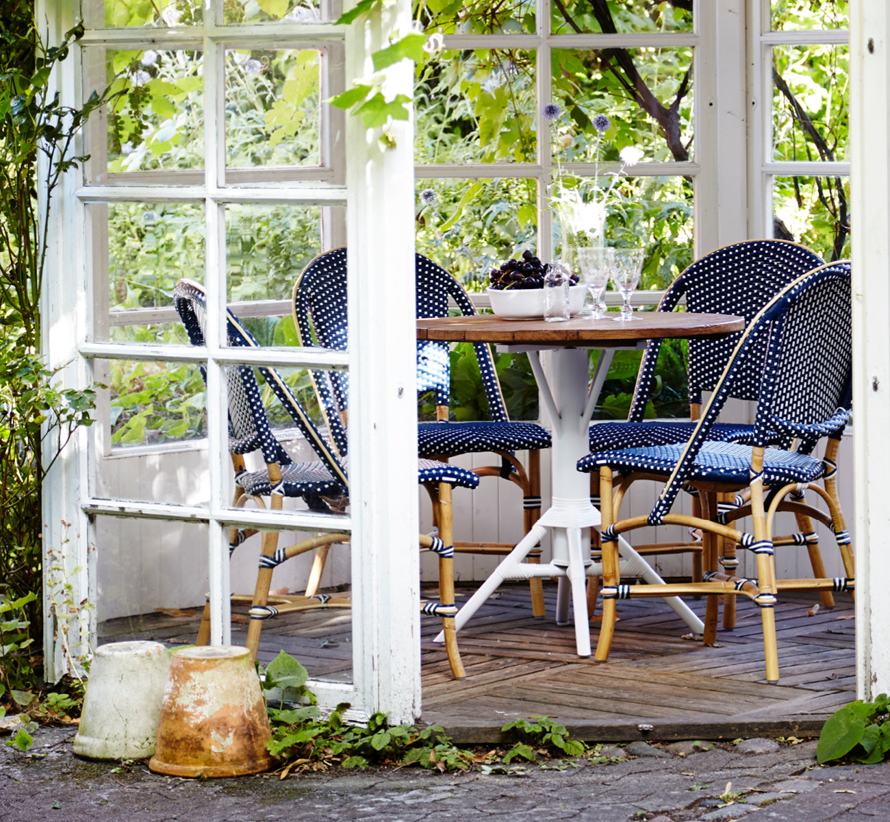 Esta es una imagen de estilo de vida de Sofie silla de comedor en navy blue w white dot artfibre skin on natual rattan frame. Estilizado en un interior luminoso.