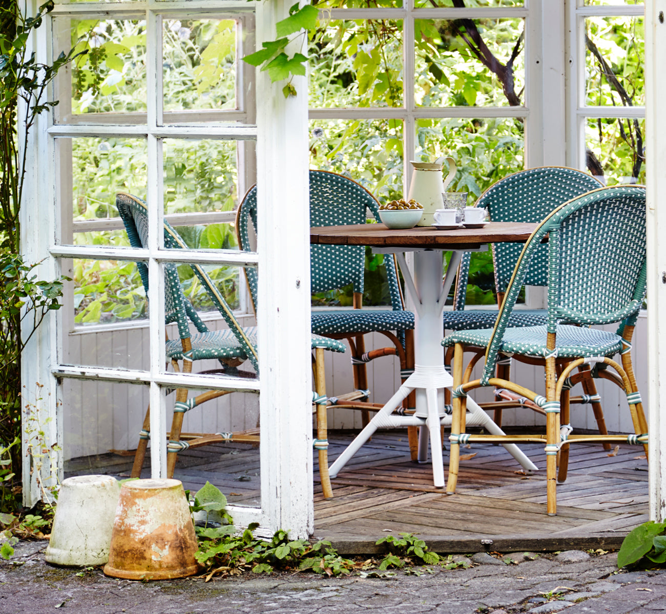 Esta es una imagen de estilo de vida de Sofie silla de comedor en salvie green w white dot artfibre skin on natual rattan frame. Estilizado en un interior luminoso.