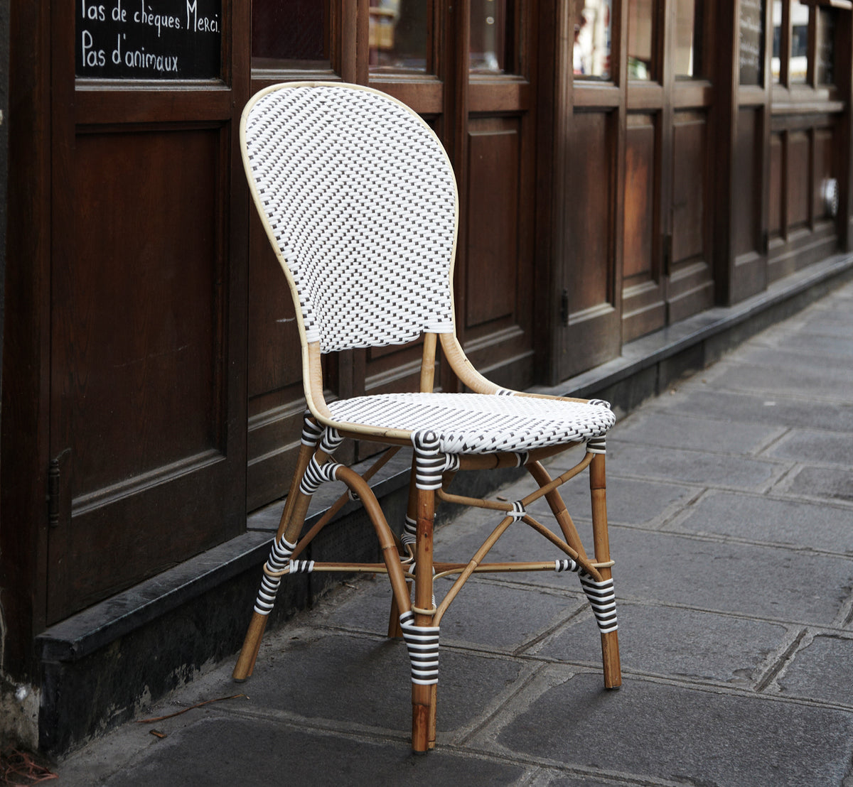 Esta es una imagen de estilo de vida de Isabell en white w cappuccino dot ArtFibre Skin on Rattan frame, en una terraza costera luminosa con vistas.