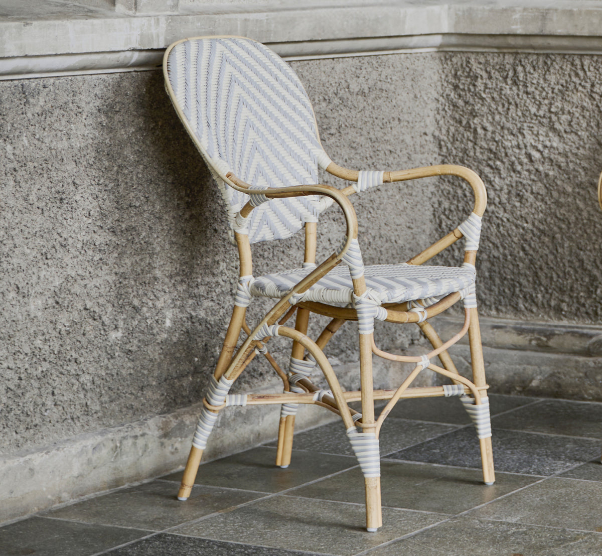 Esta es una imagen de estilo de vida de Isabell sillón de comedor en chevron Grey Ivory ArtFibre Skin on Rattan frame, en un luminoso comedor con.