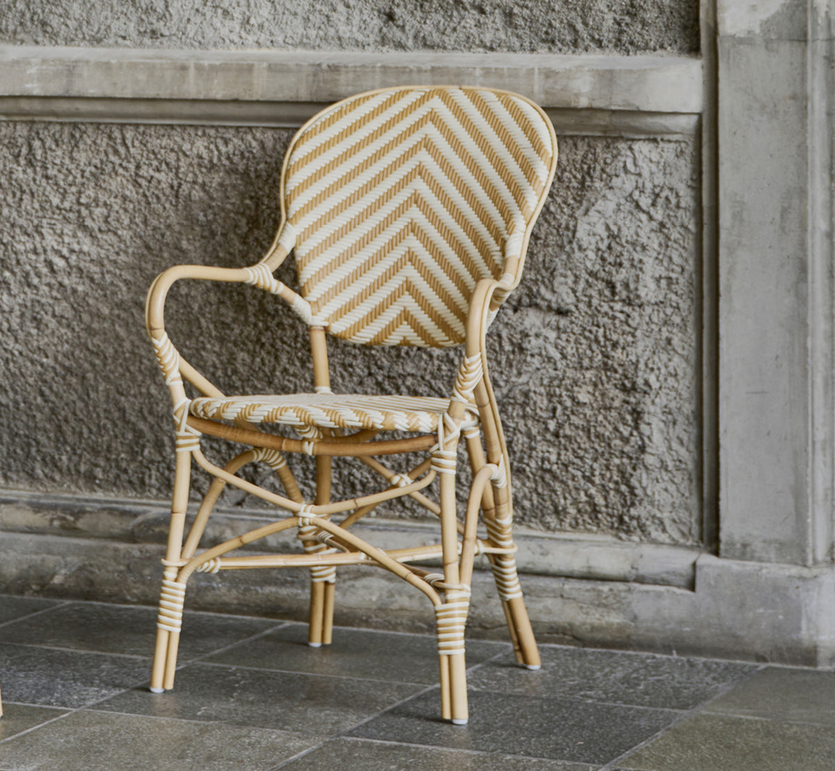 Esta es una imagen de estilo de vida de Isabell sillón de comedor en chevron Honey Ivory ArtFibre Skin on Rattan frame, en un luminoso comedor con.