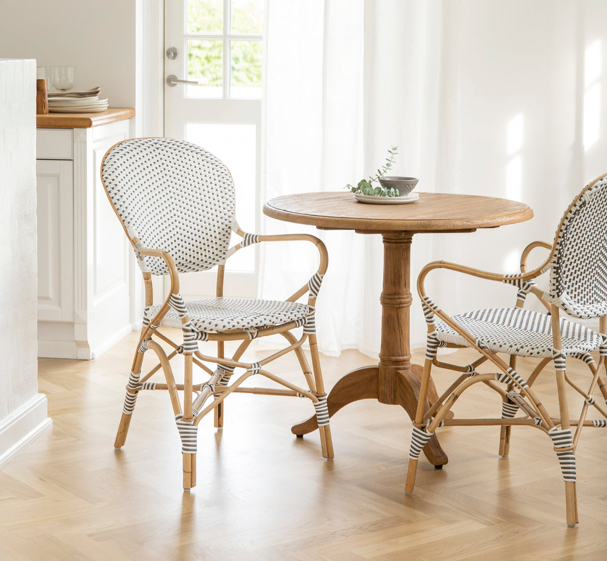 Esta es una imagen de estilo de vida de Isabell sillón de comedor en white w cappuccino dot ArtFibre Skin on Rattan frame, en un luminoso comedor con.