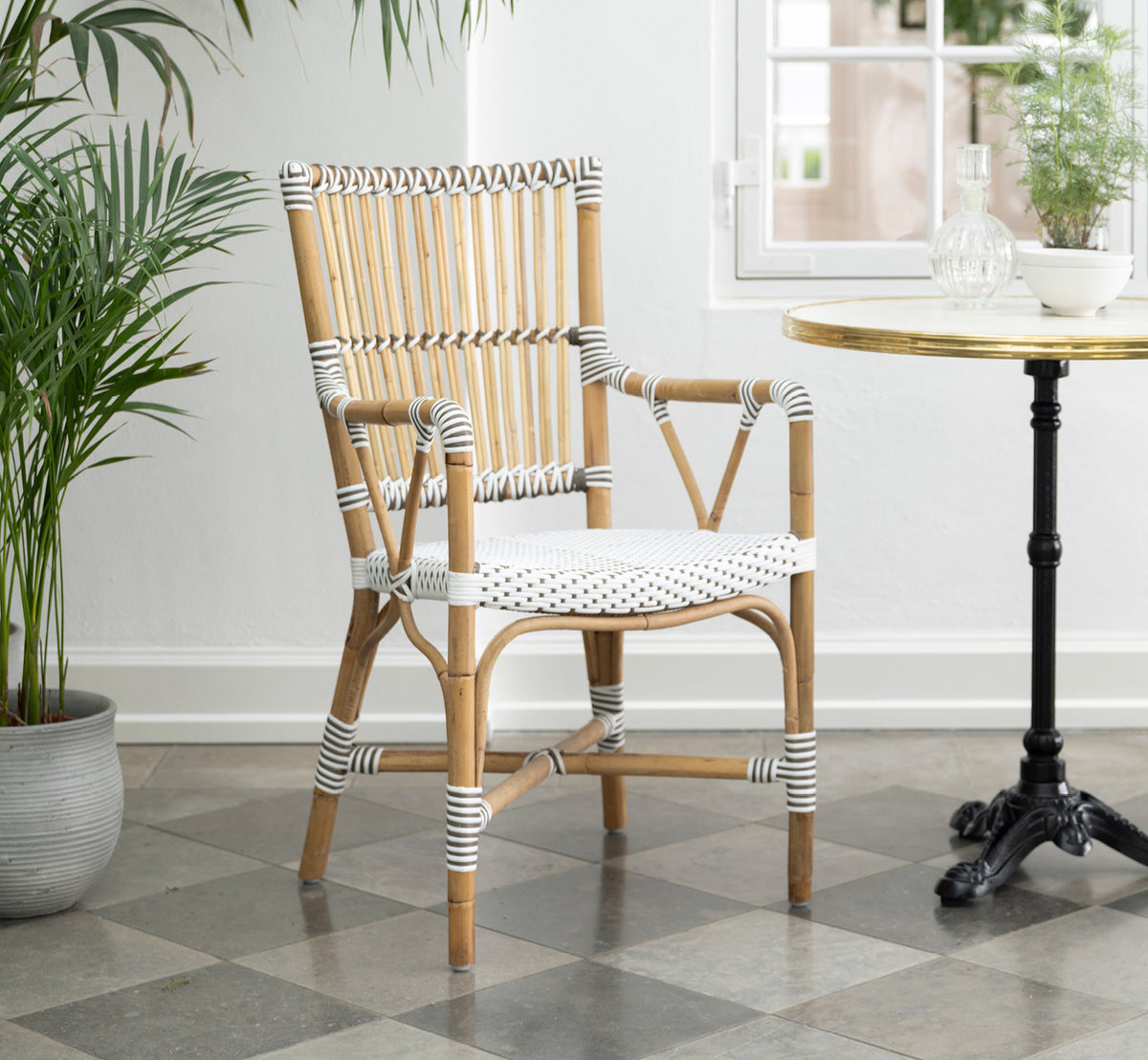 Esta es una imagen de estilo de vida de Monique sillón de comedor en white w cappuccino dot artfibre skin on rattan frame. Estilizado en un interior luminoso.