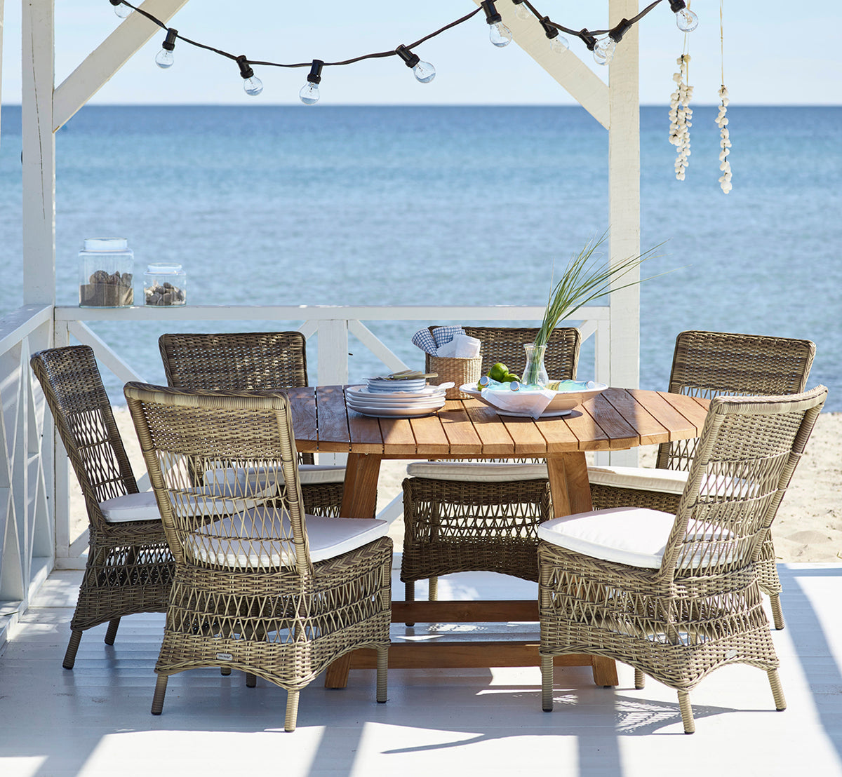 Esta es una imagen de estilo de vida de Marie Exterior Side Chair i antique grey artfibre aluminium. En un pabellón de playa preparado para cenar.