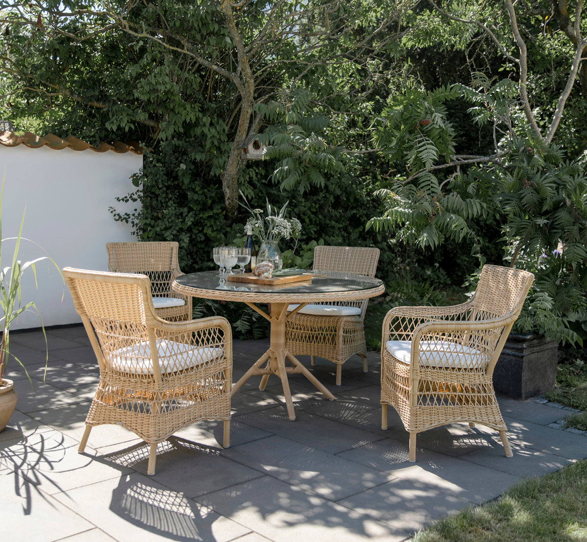 Esta es una imagen de estilo de vida de Marie sillón exterior en natural artfibre aluminium. Estilizado en un interior luminoso.