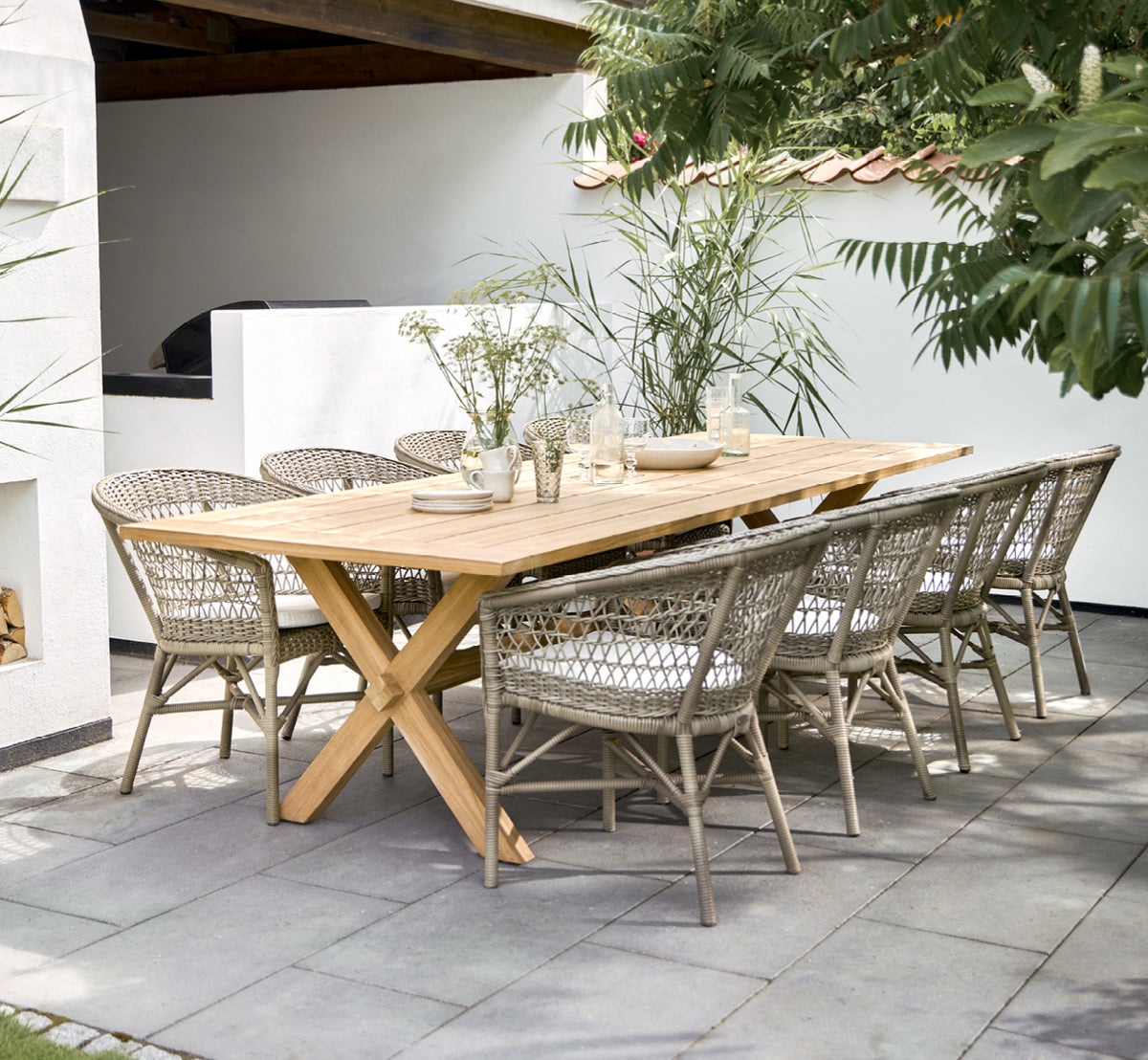 Esta es una imagen de estilo de vida de Emma silla de comedor exterior en antique Grey ArtFibre Aluminium, en una terraza costera luminosa con techo.