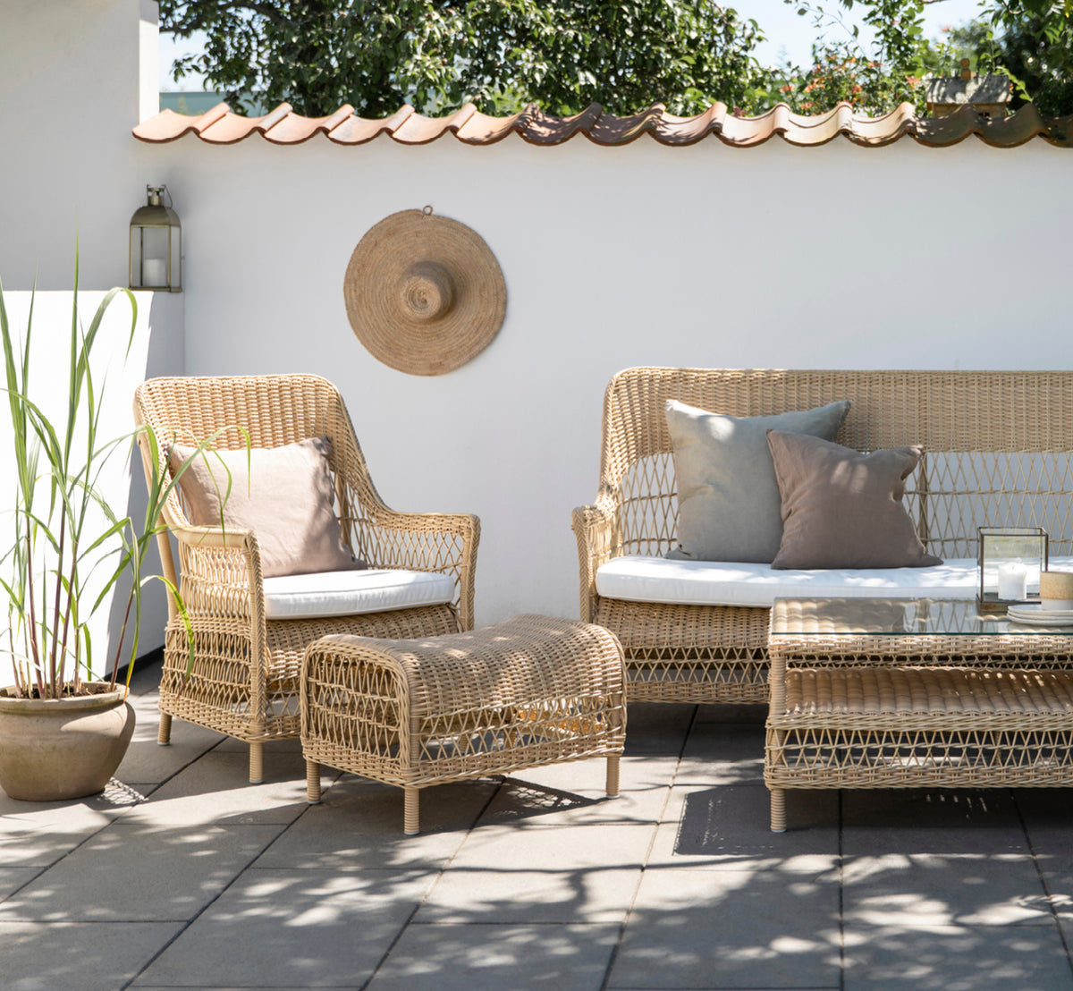 Esta es una imagen de estilo de vida de Dawn sillón lounge en natural ArtFibre Aluminium, en una terraza costera con vistas al mar, gramíneas de.