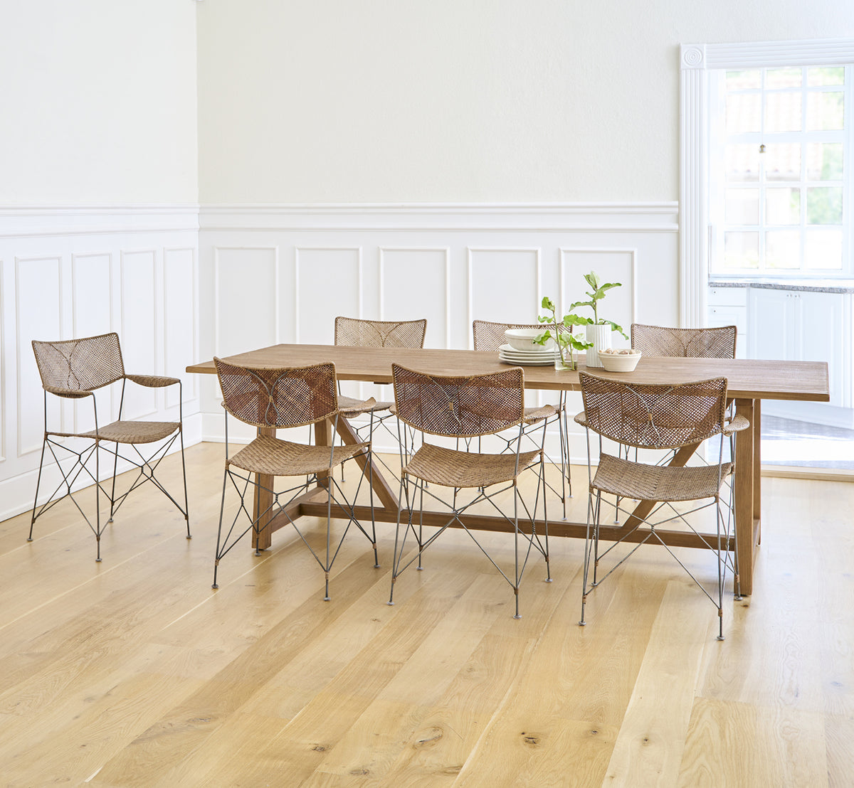 Esta es una imagen de estilo de vida de Lucas Teak Dining Table 240X100 cm en teak indoor. Combinada con sillas modernas en una sala luminosa con paredes de paneles blancos.