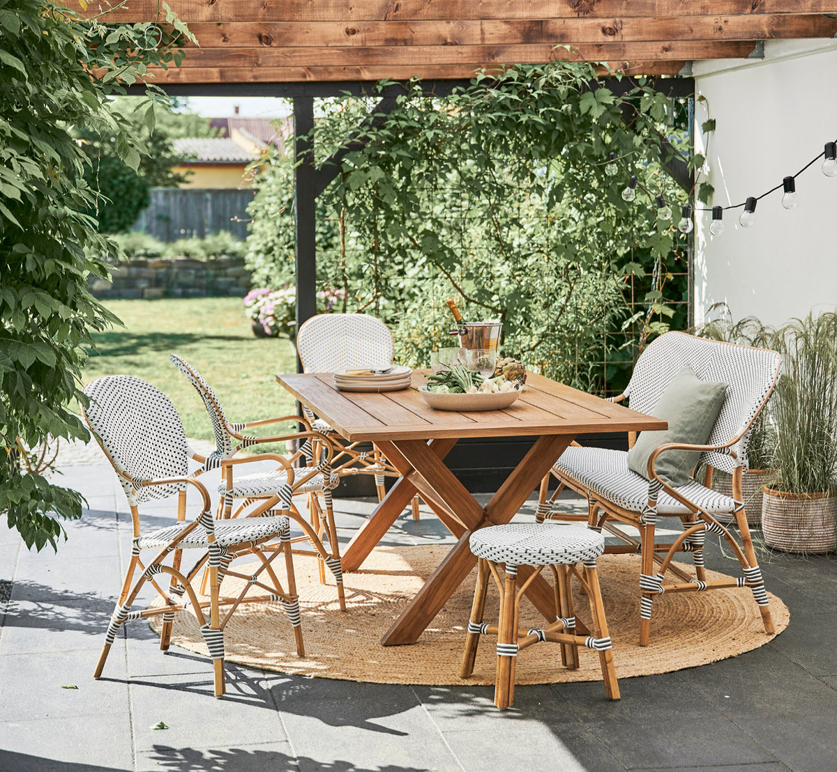 Esta es una imagen de estilo de vida de Colonial mesa 160 en outdoor Teak, en una terraza junto a la playa con cubierta de madera blanca y vistas al.