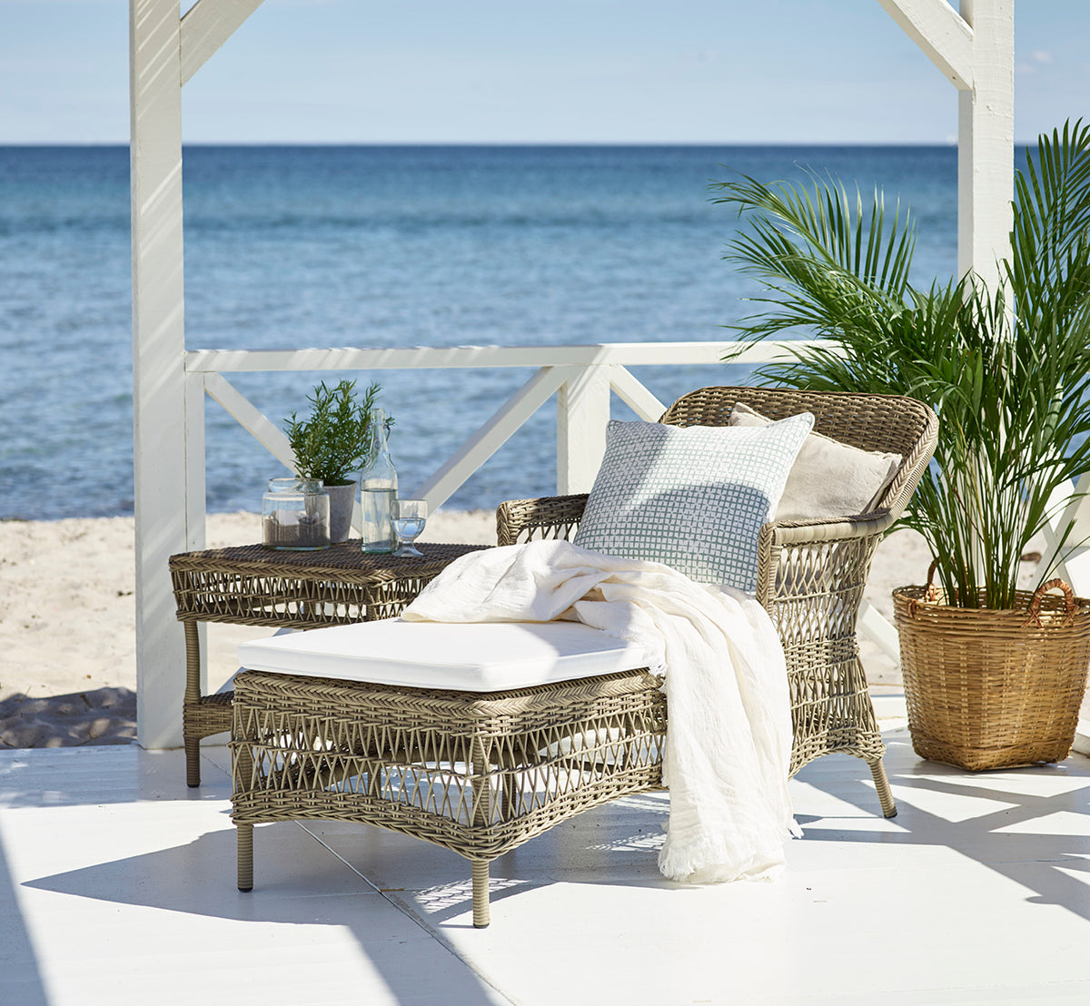 Esta es una imagen de estilo de vida de Olivia Exterior Sunbed i antique grey artfibre aluminium. En un patio de piedra rodeado de jardín.