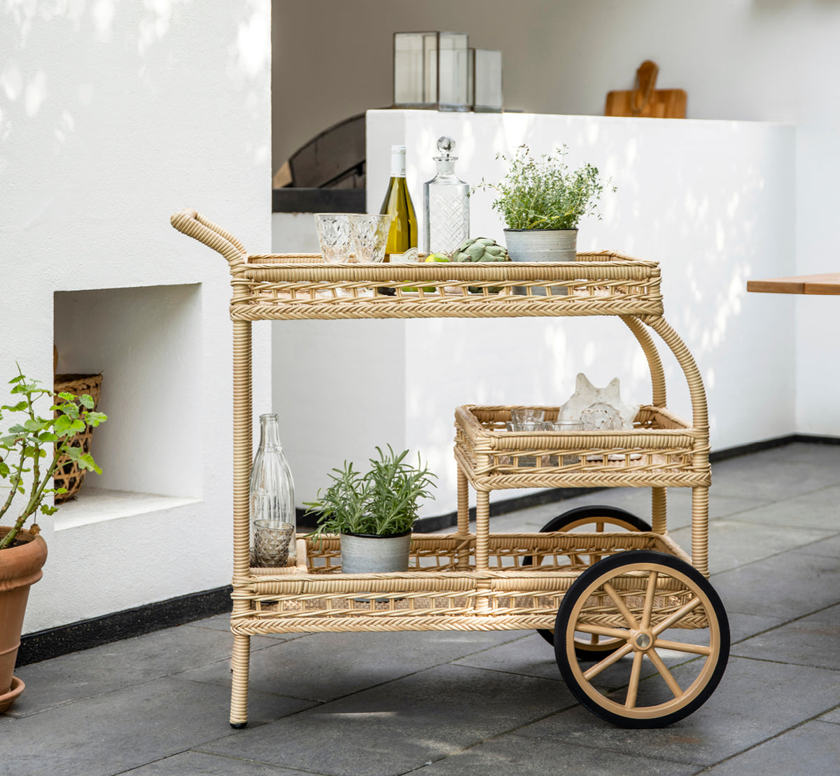 Esta es una imagen de estilo de vida de James en natural artfibre aluminium, en una terraza de playa bajo una pérgola blanca con vistas al mar.