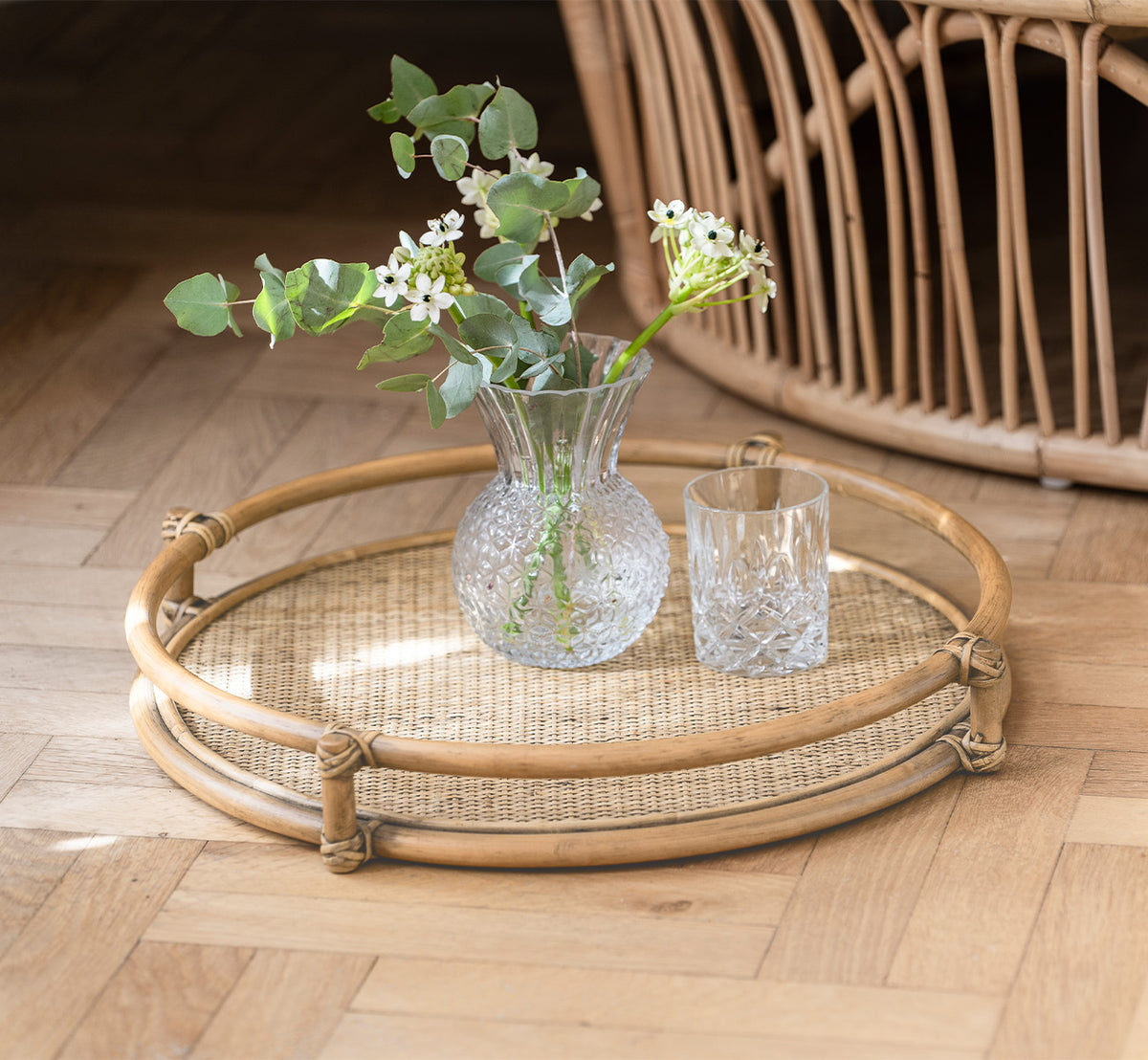 Esta es una imagen de estilo de vida de Andreas bandeja en natural Rattan, en un interior luminoso con parqué en espiga.