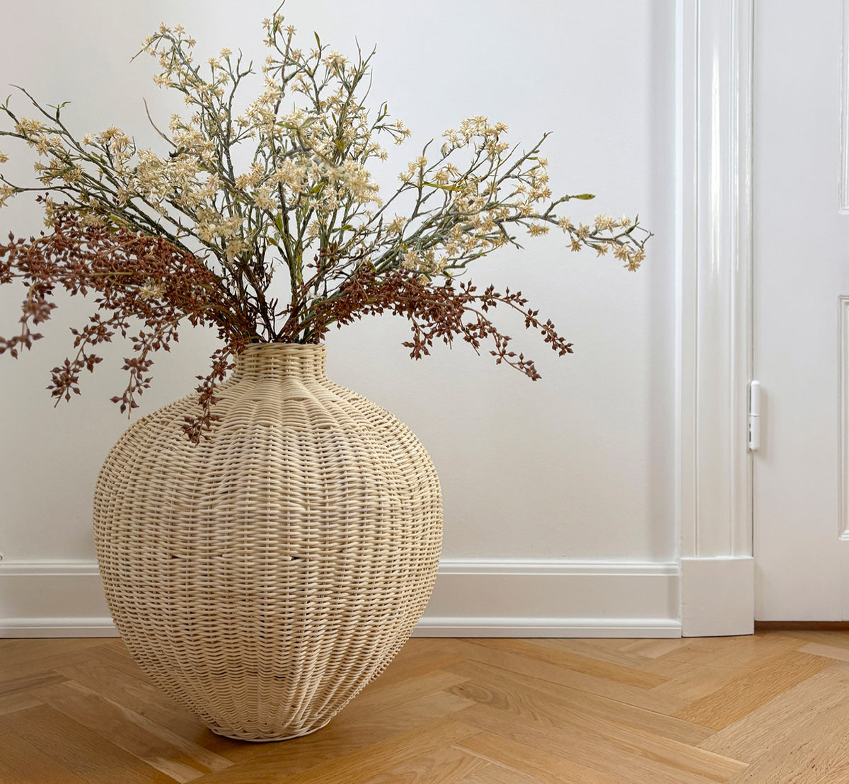 Esta es una imagen de estilo de vida de Flumen cesta en natural core weave iron frame, en un interior blanco y luminoso con revestimiento de pared,.