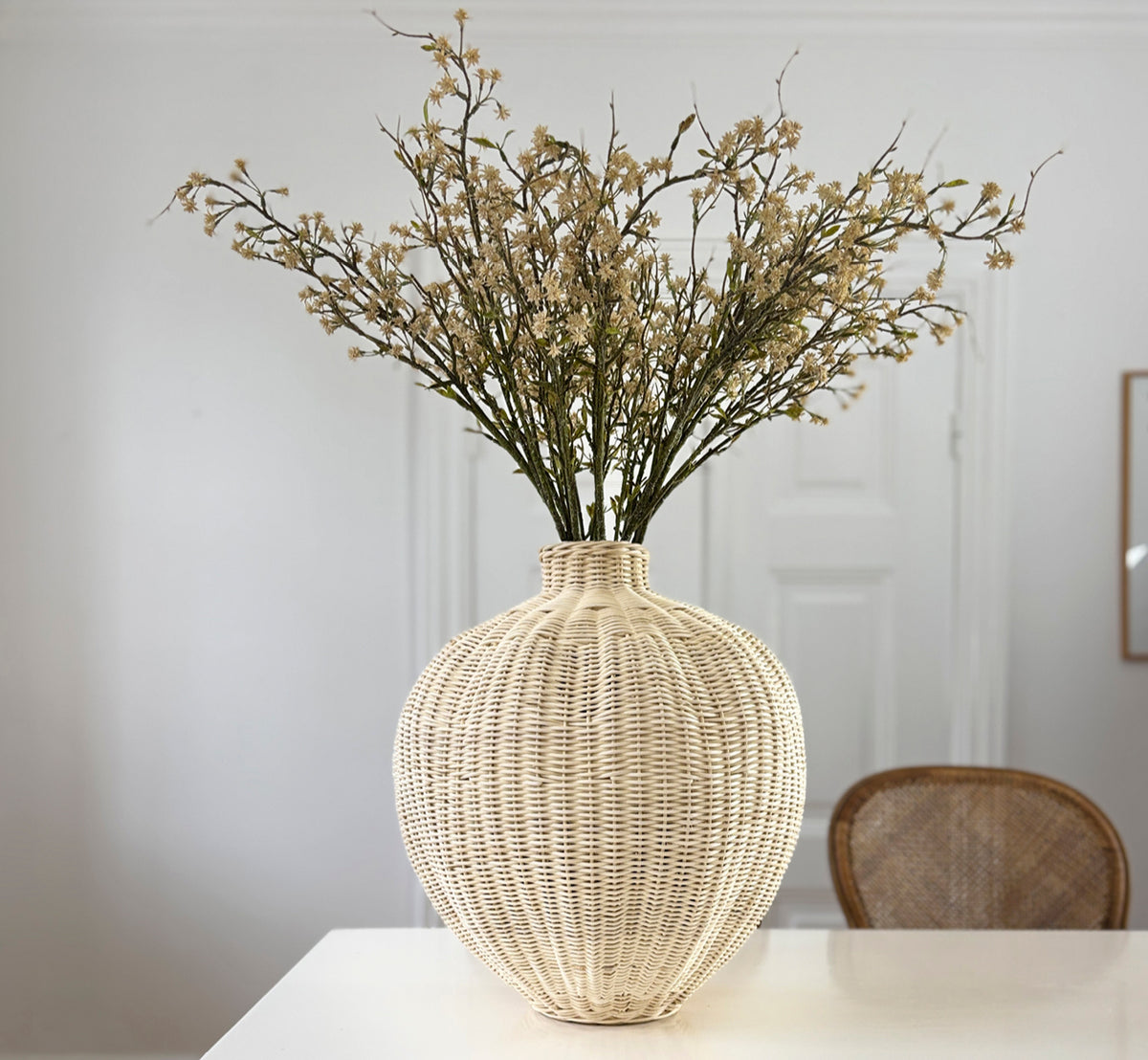 Esta es una imagen de estilo de vida de Flumen cesta en natural core weave iron frame, en un interior blanco y luminoso con revestimiento de pared,.