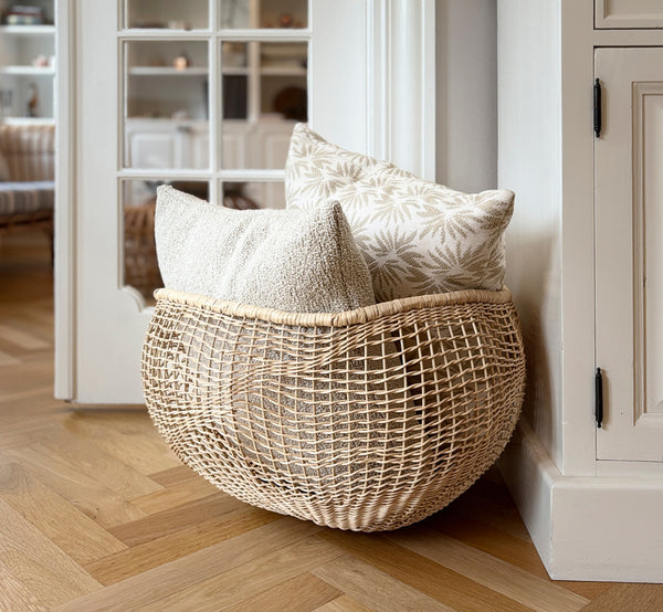 Esta es una imagen de estilo de vida de Folia cesta en natural core weave iron frame, en un interior blanco y luminoso con revestimiento de pared,.