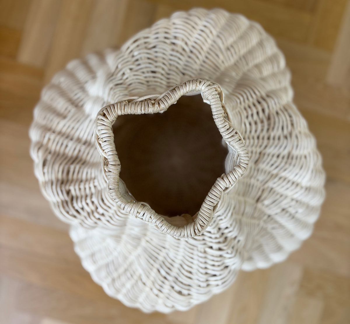 Esta es una imagen de estilo de vida de Solaris Basket Ø40 cm en natural core weave iron frame. Estilizada con flores secas junto a una puerta blanca sobre parqué.