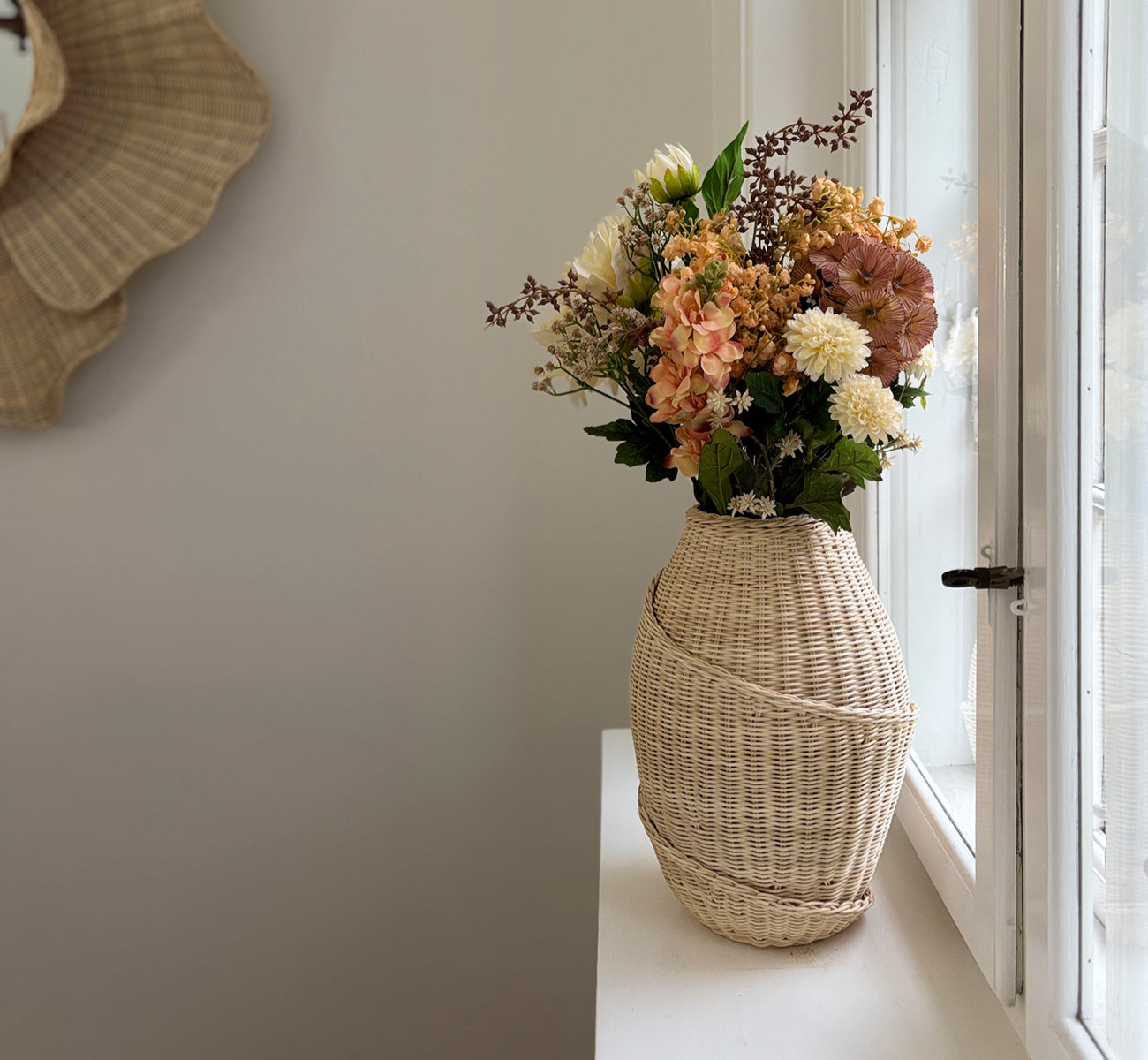 Esta es una imagen de estilo de vida de Floris cesta en natural core weave iron frame, en un interior blanco y luminoso con revestimiento de pared,.