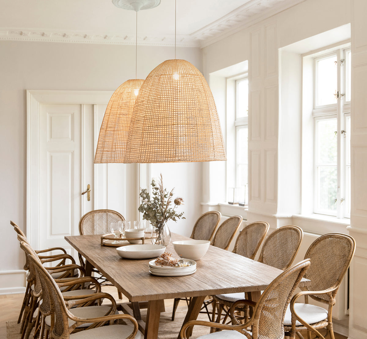 Esta es una imagen de estilo de vida de Showroom pantalla de lámpara en natural core weave artfibre & aluminium. Iluminando una mesa de comedor con sillas de ratán debajo.