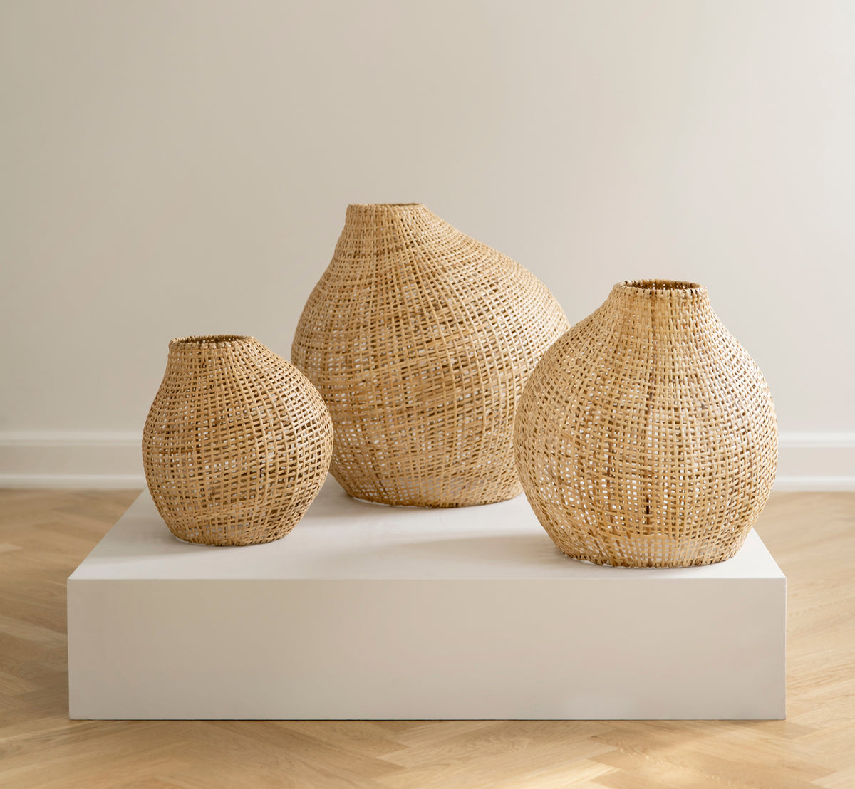 Esta es una imagen de estilo de vida de Figura pantalla de pie en light natural weave rattan, expuesto sobre una plataforma blanca ante un fondo de.