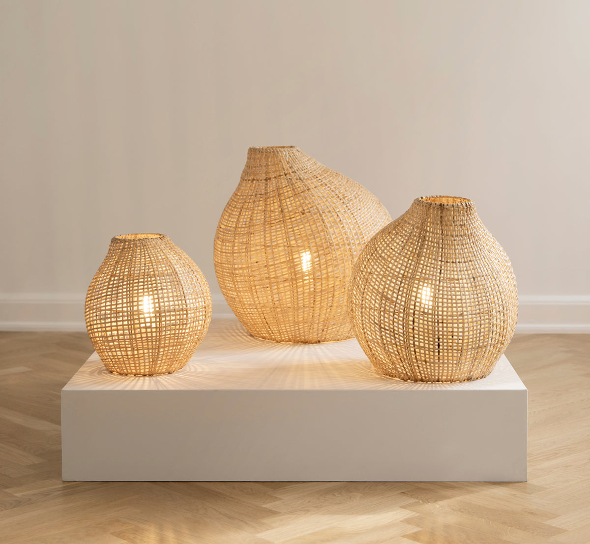 Esta es una imagen de estilo de vida de Figura pantalla de pie en light natural weave rattan, expuesto sobre una plataforma blanca ante un fondo de.