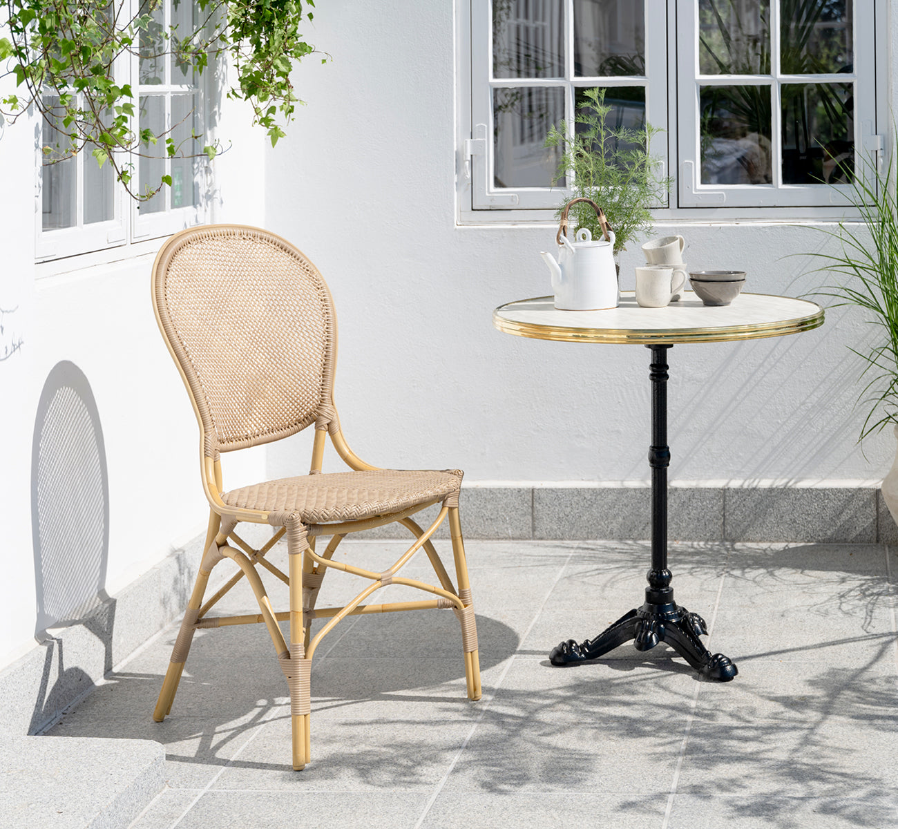 Esta es una imagen de estilo de vida de Lyon mesa de café Versalite Marble Ø70 cm en cast iron. Patio con silla de comedor y juego de café sobre la mesa.