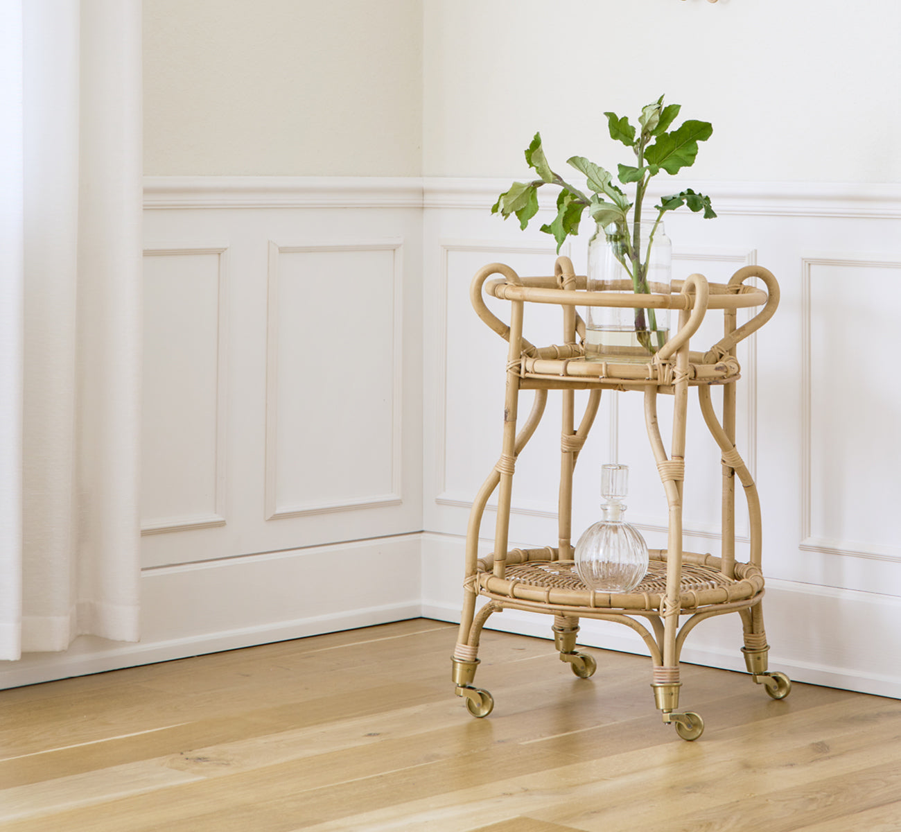 Esta es una imagen de estilo de vida de Fratellino carrito en polished Natural Rattan, en un interior clásico con elaboradas puertas de paneles.