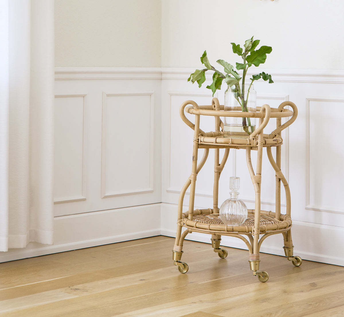 Esta es una imagen de estilo de vida de Fratellino carrito en polished Natural Rattan, en un interior clásico con elaboradas puertas de paneles.