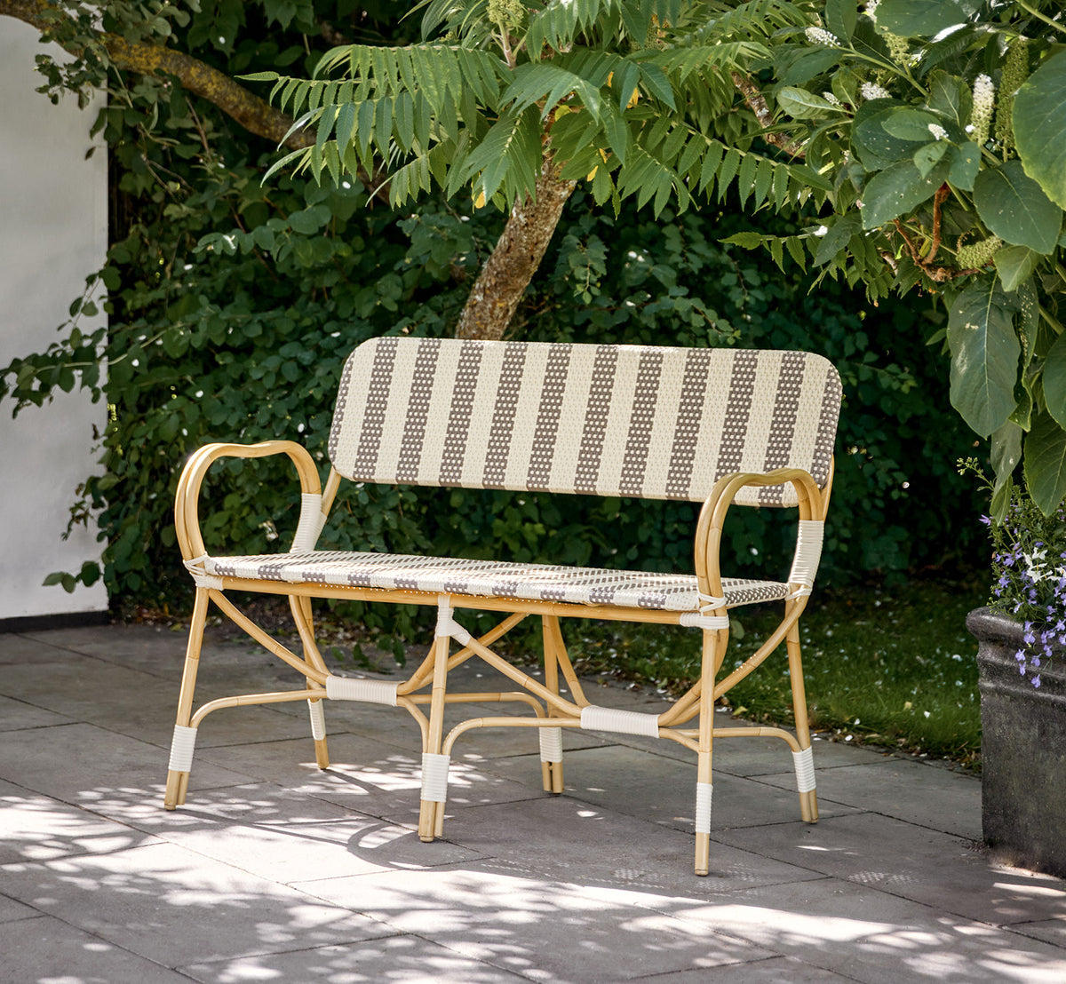 Esta es una imagen de estilo de vida de Bistro Exterior banco en natural Aluminium ArtFibre, en un café de jardín al aire libre con una mesa de.