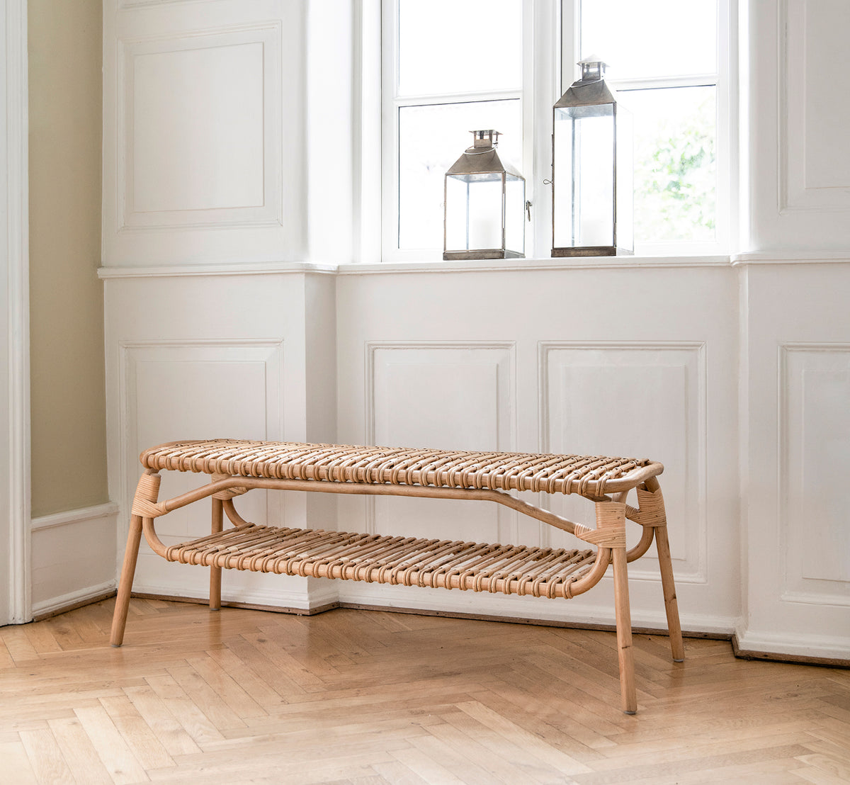 Esta es una imagen de estilo de vida de Machiya Bench en natural skin on rattan. Estilizado en un interior luminoso.