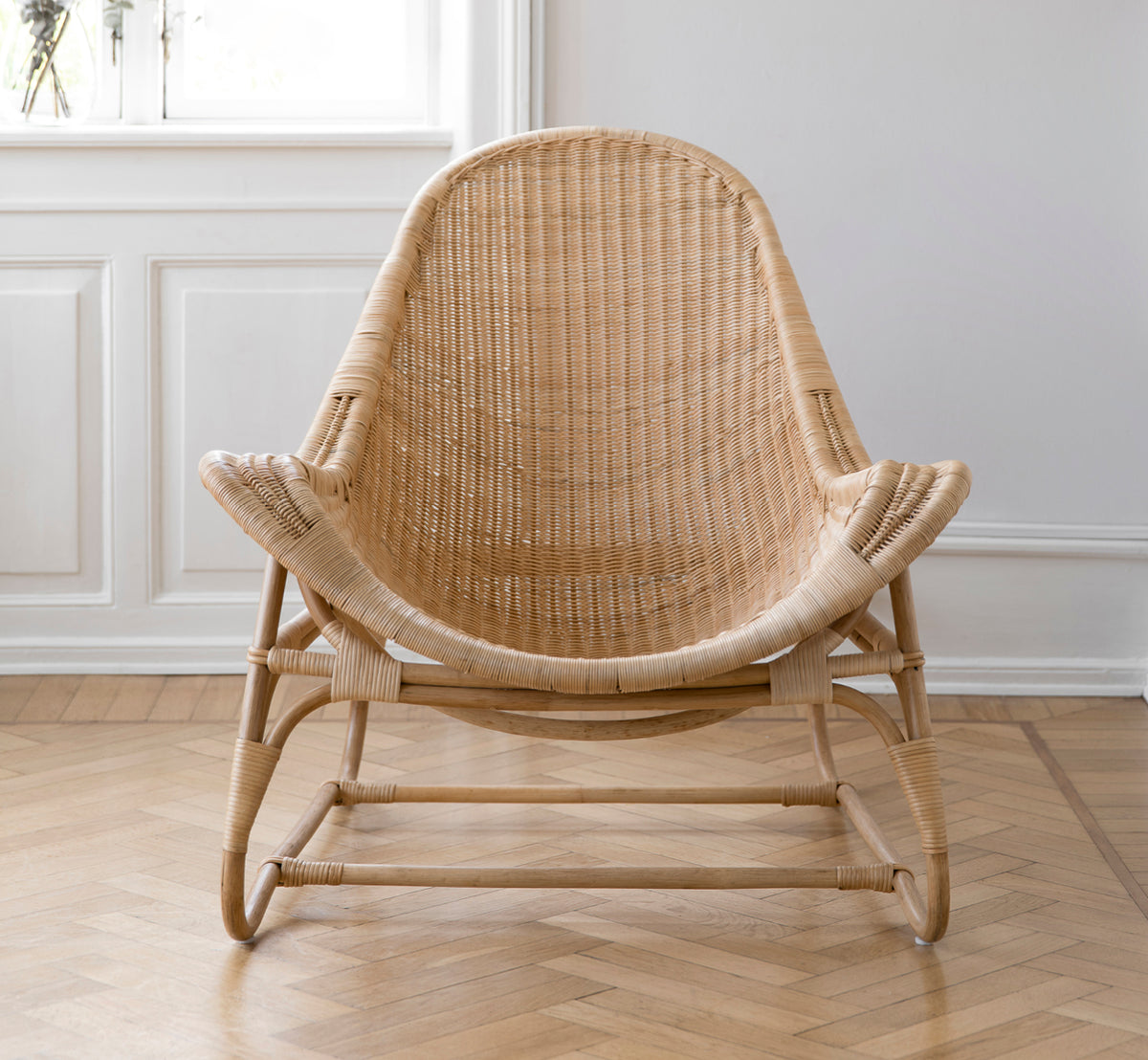 Esta es una imagen de estilo de vida de Pacifique sillón lounge en natural core weave rattan frame. Estilizado en un interior luminoso.