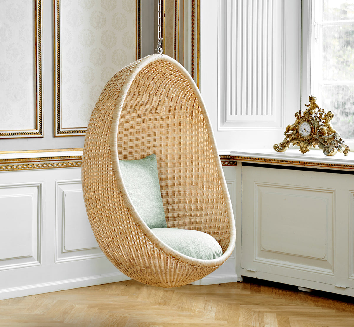 Esta es una imagen de estilo de vida de Hanging silla colgante en natural core weave Rattan frame, en un elegante interior clásico con elaboradas.