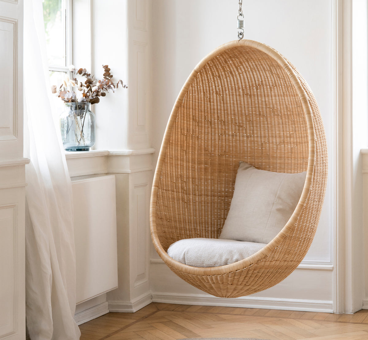 Esta es una imagen de estilo de vida de Hanging silla colgante en natural core weave Rattan frame, en un elegante interior clásico con elaboradas.