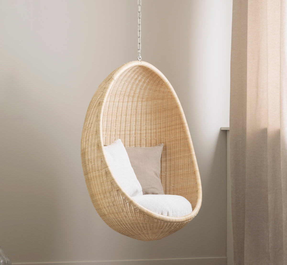 Esta es una imagen de estilo de vida de Hanging silla colgante en natural core weave Rattan frame, en un elegante interior clásico con elaboradas.