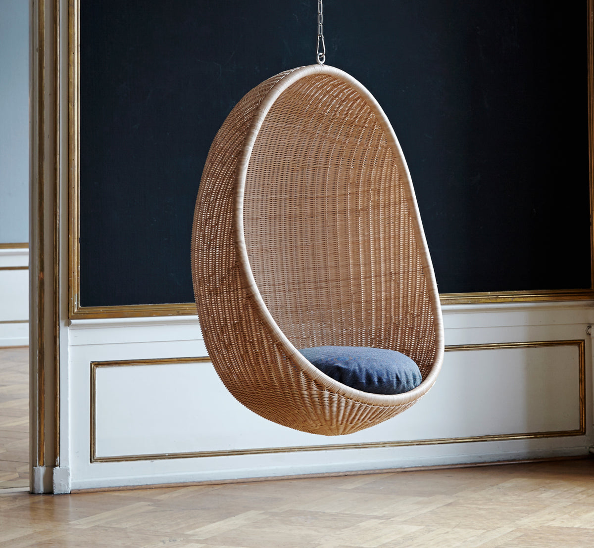 Esta es una imagen de estilo de vida de Hanging silla colgante en natural core weave Rattan frame, en un elegante interior clásico con elaboradas.