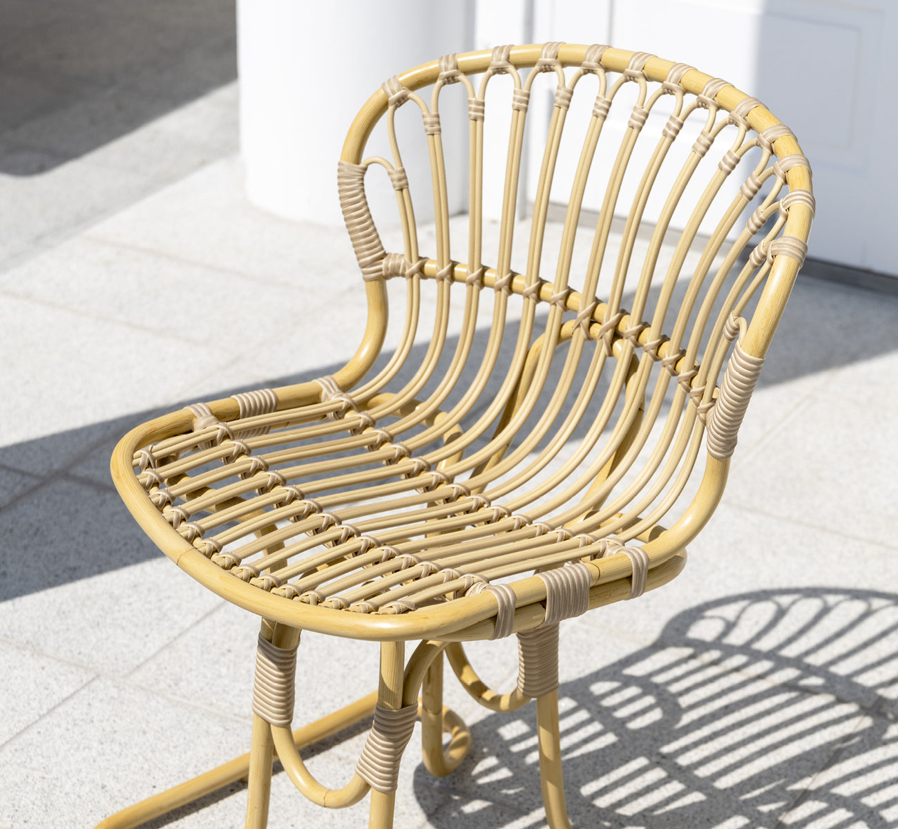 Esta es una imagen de estilo de vida de Rita silla de comedor exterior en natural aluminium artfibre. Combinado con una mesa bistró en una terraza blanca con columnas.