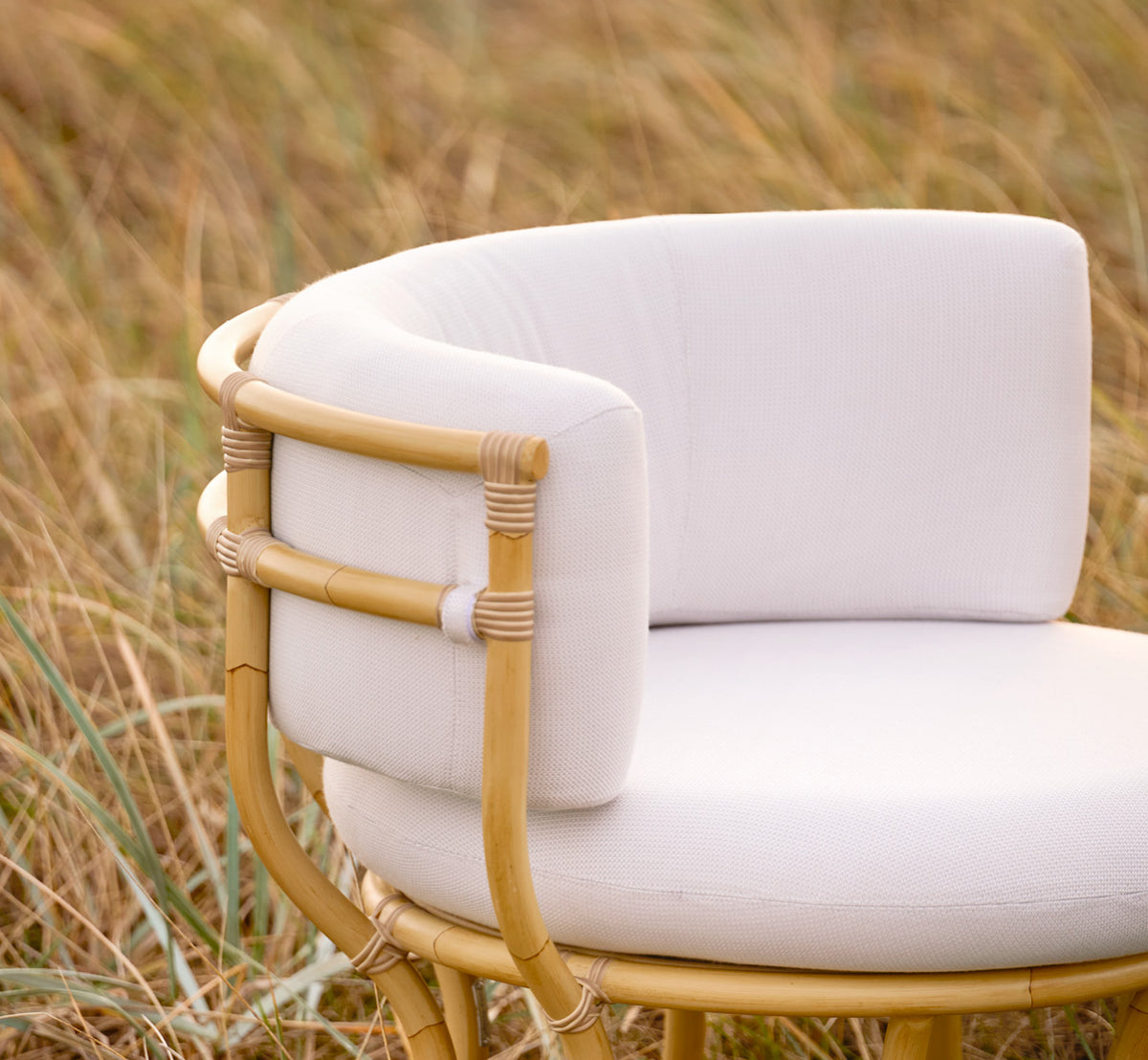 Esta es una imagen de estilo de vida de Coco sillón lounge exterior en natural Aluminium ArtFibre, en una terraza costera abierta al atardecer con.