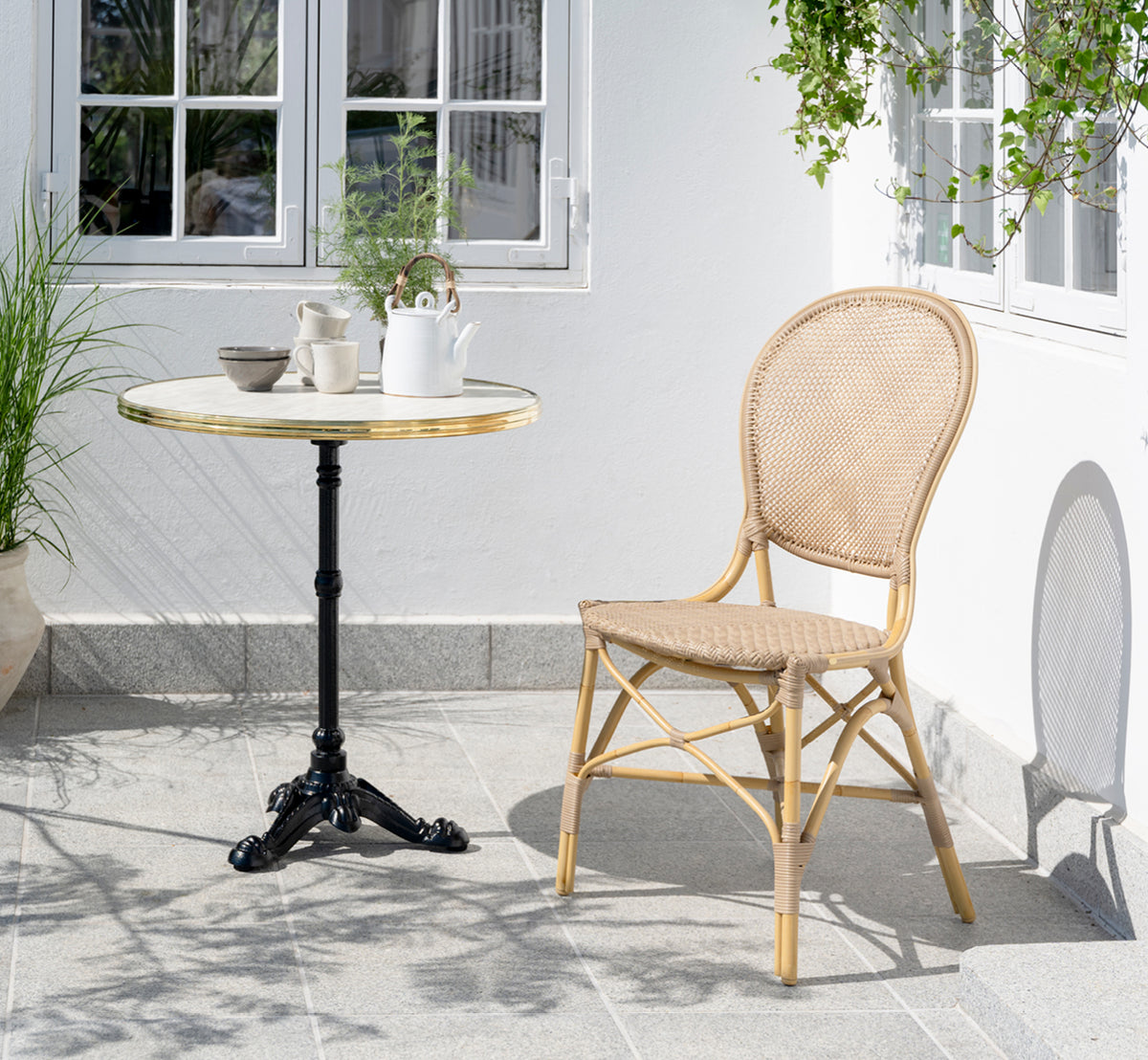 Esta es una imagen de estilo de vida de Rossini silla de comedor exterior en natural aluminium artfibre. Estilizado en un interior luminoso.