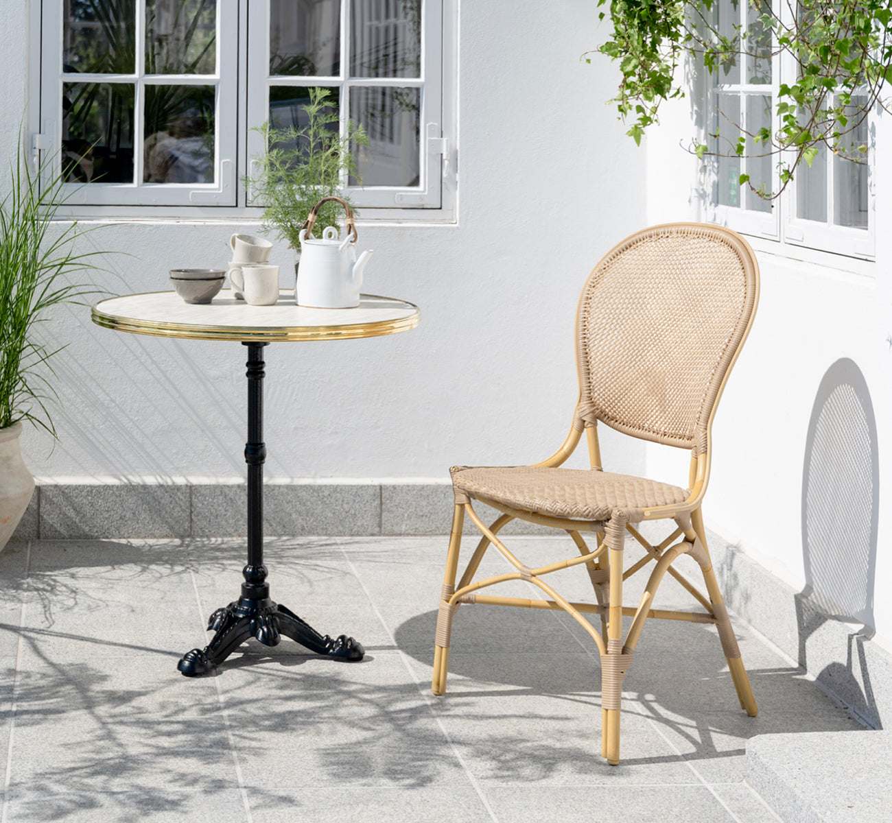 Esta es una imagen de estilo de vida de Rossini silla de comedor exterior en natural aluminium artfibre. Estilizado en un interior luminoso.
