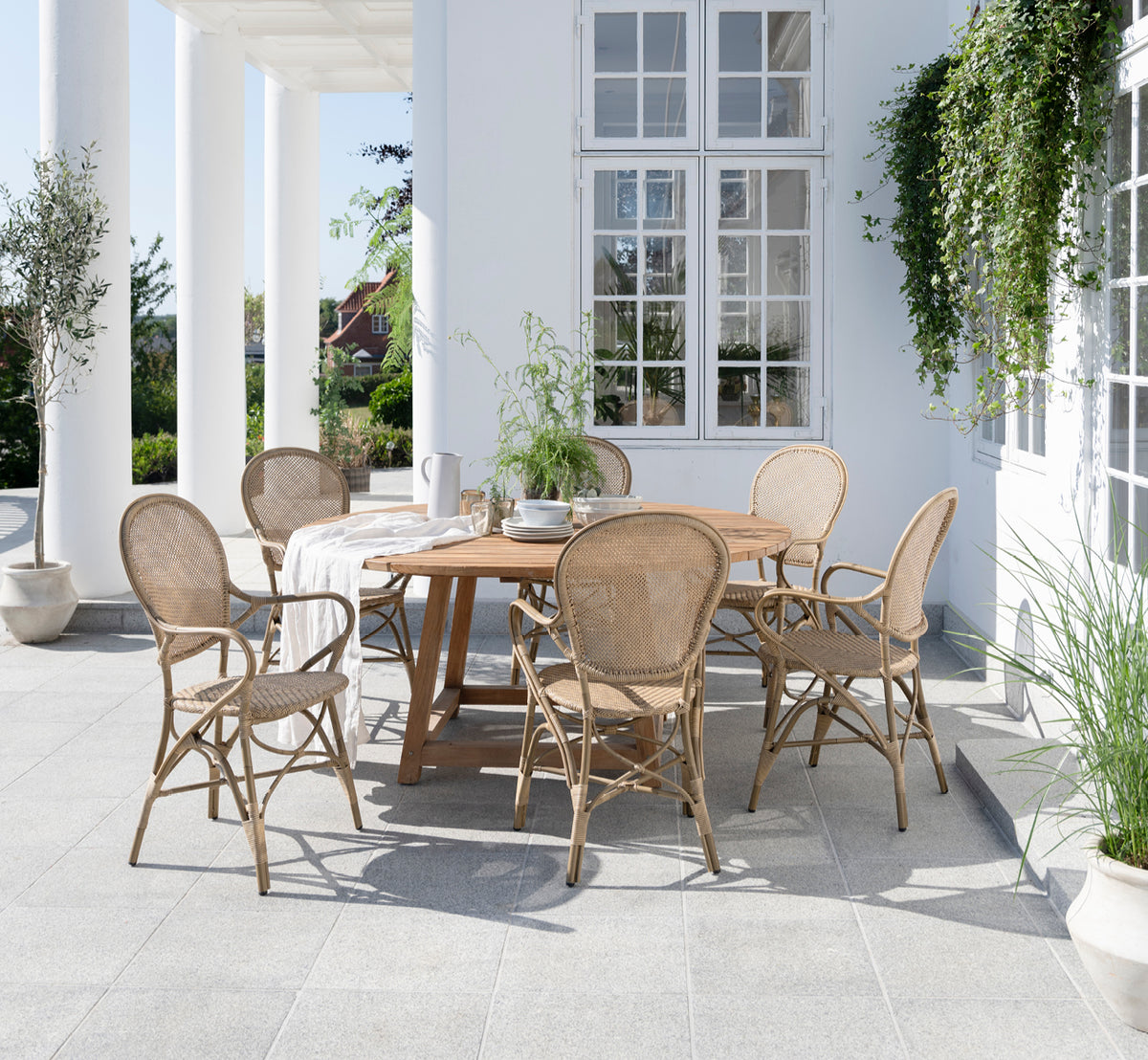 Esta es una imagen de estilo de vida de Rossini sillón de comedor exterior en antique aluminium artfibre. Estilizado en un interior luminoso.