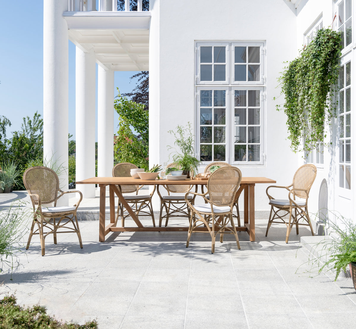 Esta es una imagen de estilo de vida de Rossini sillón de comedor exterior en antique aluminium artfibre. Estilizado en un interior luminoso.