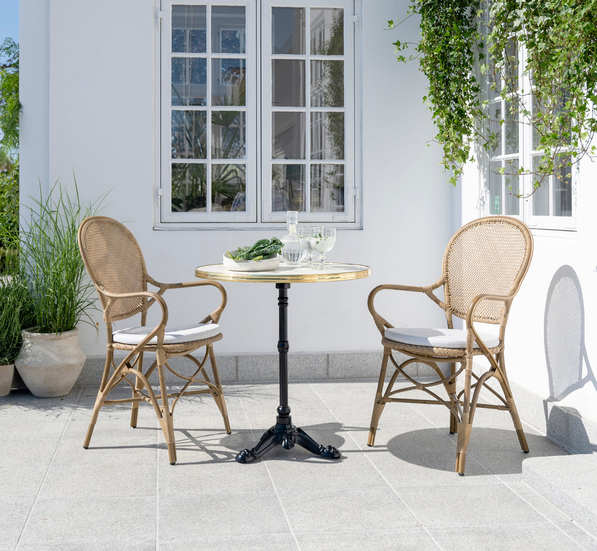 Esta es una imagen de estilo de vida de Rossini sillón de comedor exterior en antique aluminium artfibre. Estilizado en un interior luminoso.