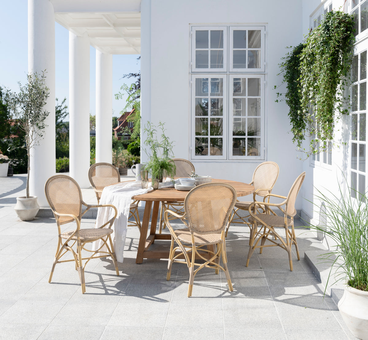 Esta es una imagen de estilo de vida de Rossini sillón de comedor exterior en natural aluminium artfibre. Estilizado en un interior luminoso.