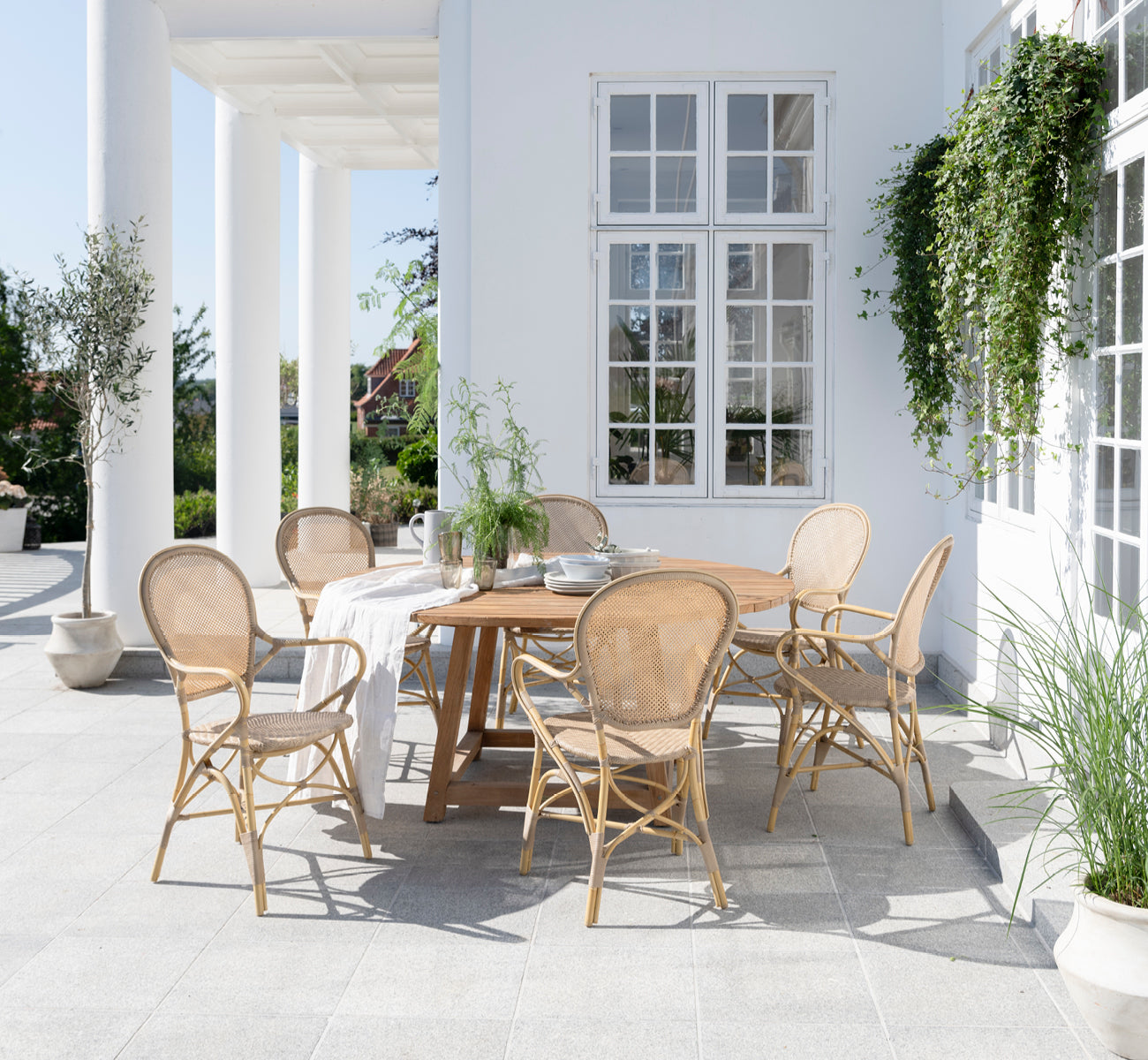 Esta es una imagen de estilo de vida de Rossini sillón de comedor exterior en natural aluminium artfibre. Estilizado en un interior luminoso.