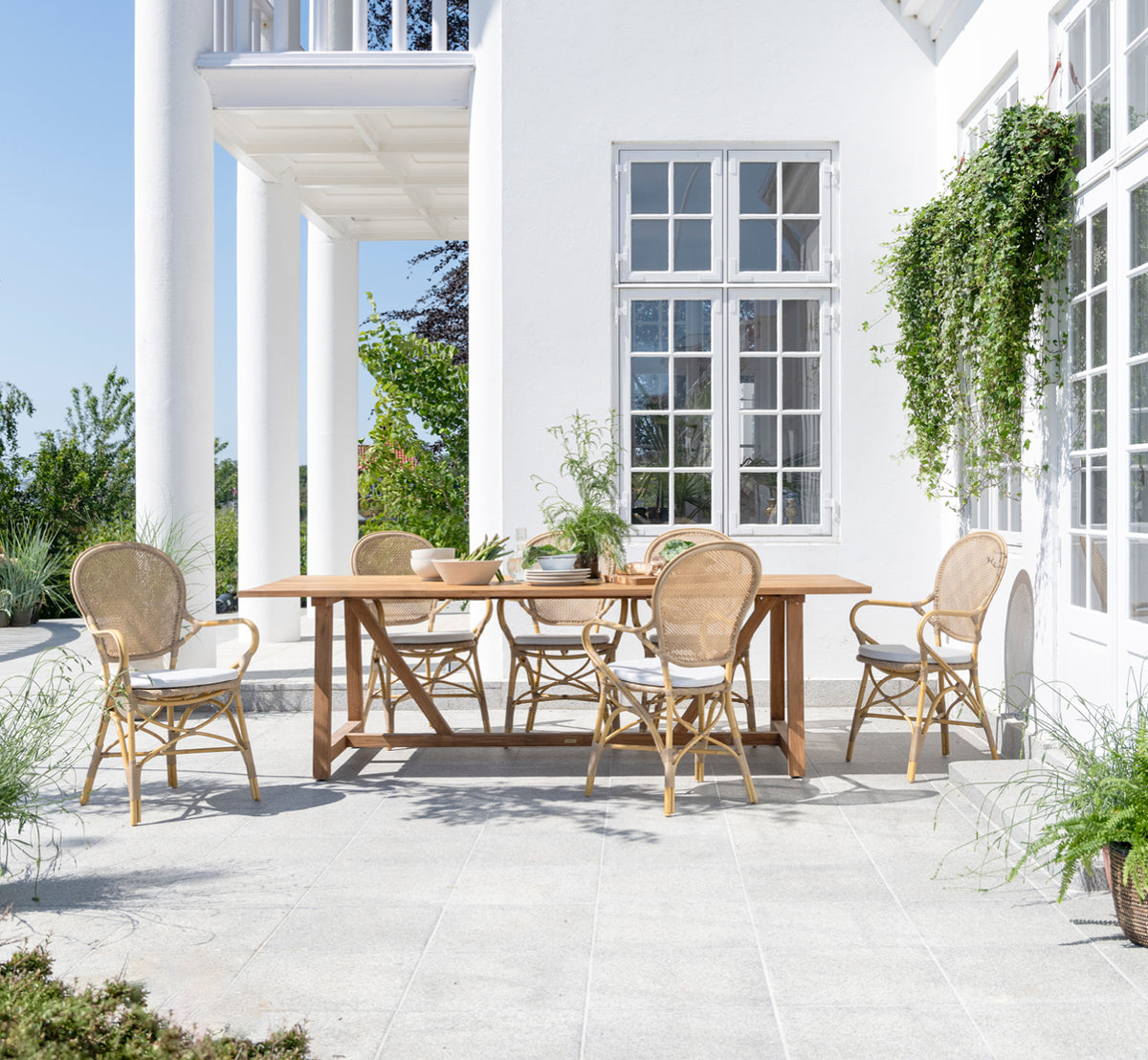 Esta es una imagen de estilo de vida de Rossini sillón de comedor exterior en natural aluminium artfibre. Estilizado en un interior luminoso.