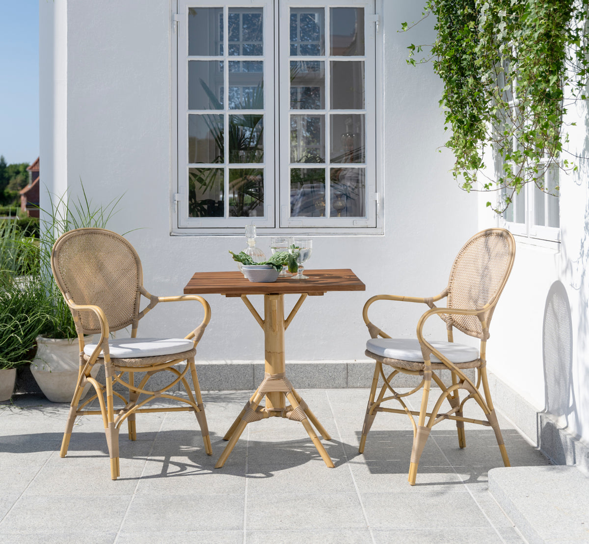 Esta es una imagen de estilo de vida de Rossini sillón de comedor exterior en natural aluminium artfibre. Estilizado en un interior luminoso.